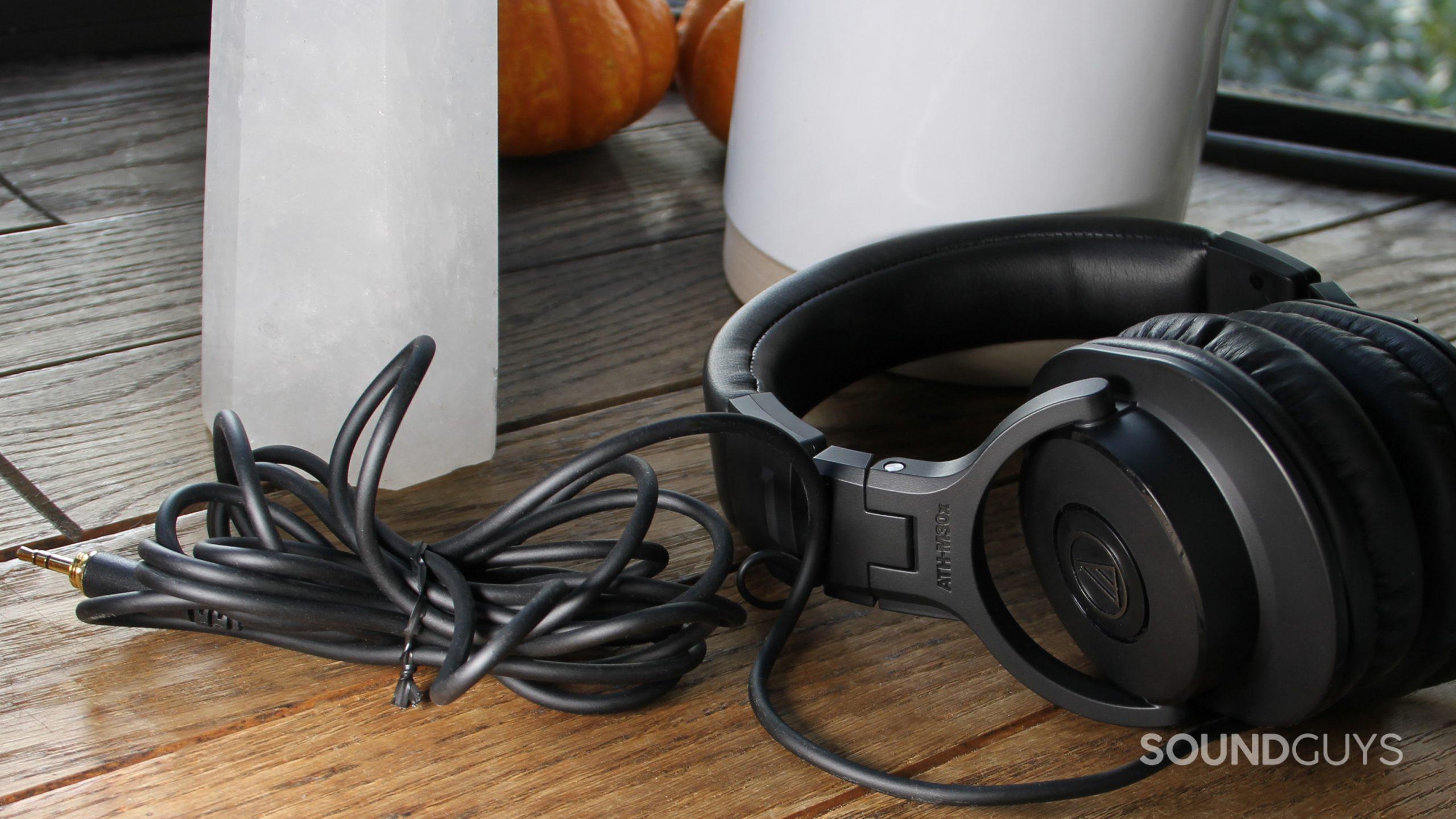 The Audio-Technica ATH-M30x resting on a wood surface with the cable folded up.