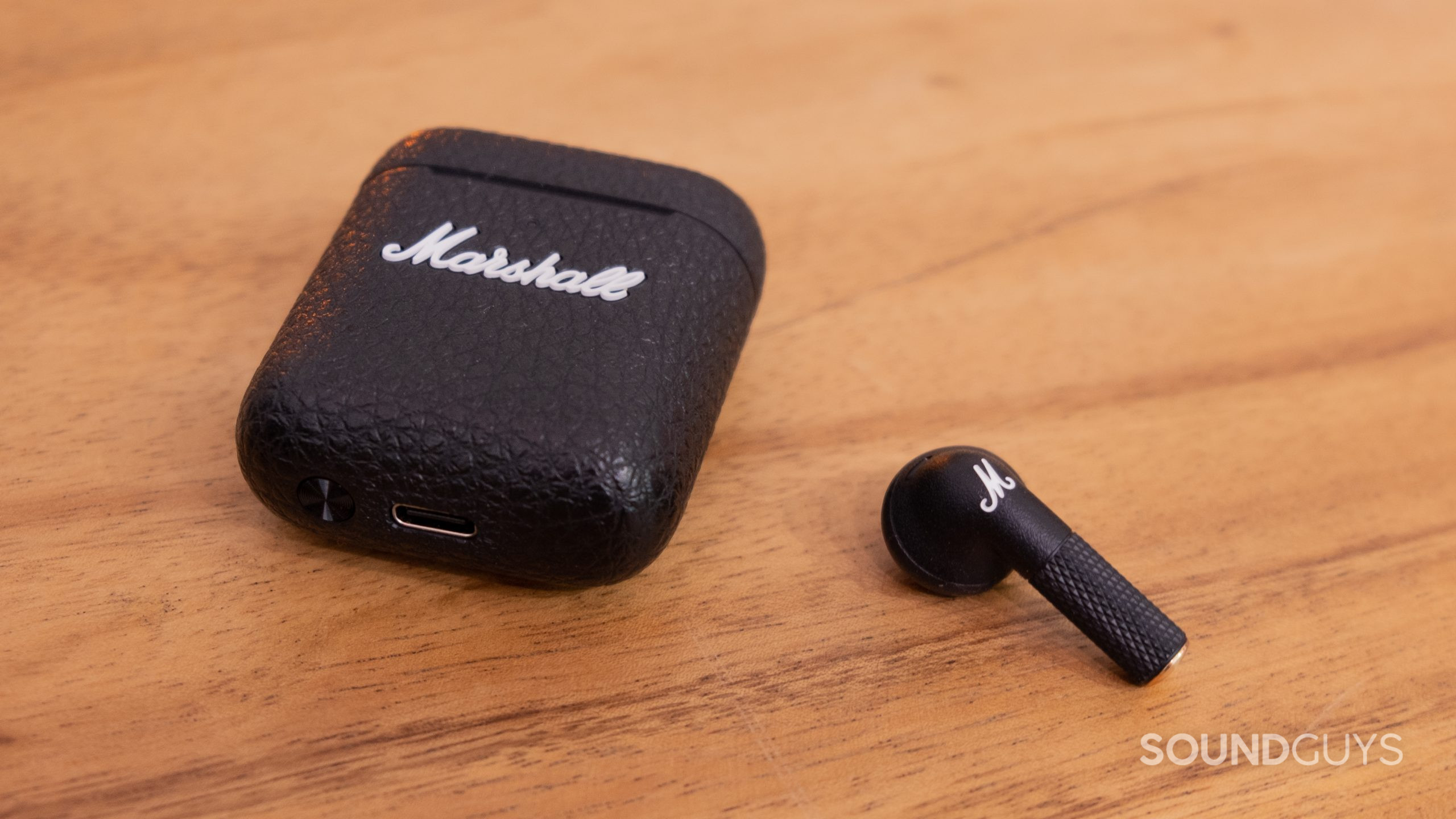 On a wood surface a single bud and the closed case of the Marshall Minor III.