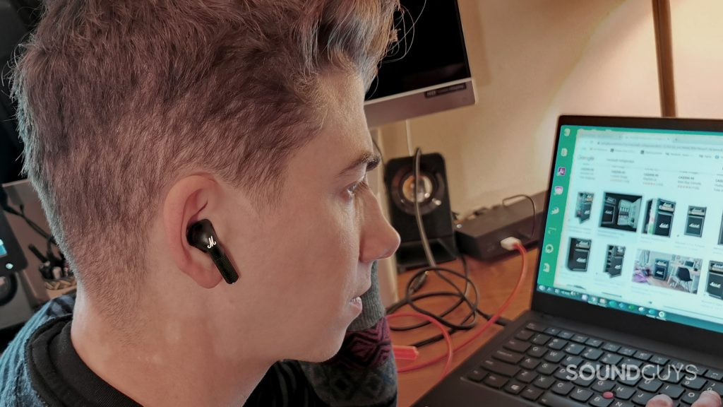 A man wears the Marshall Minor III while looking at a laptop.
