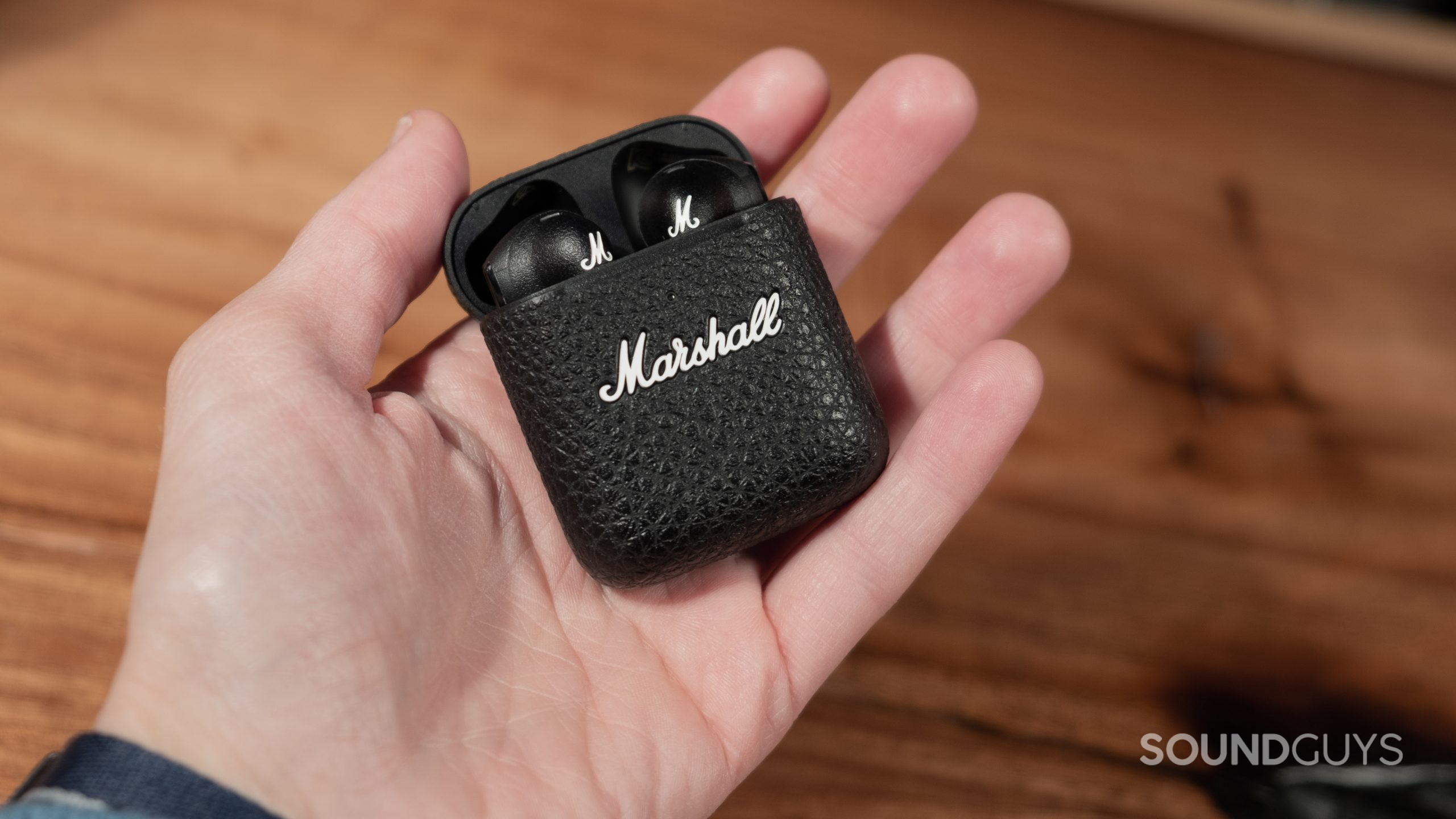 In a hand the Marshall Minor III with the lid open showing the buds.