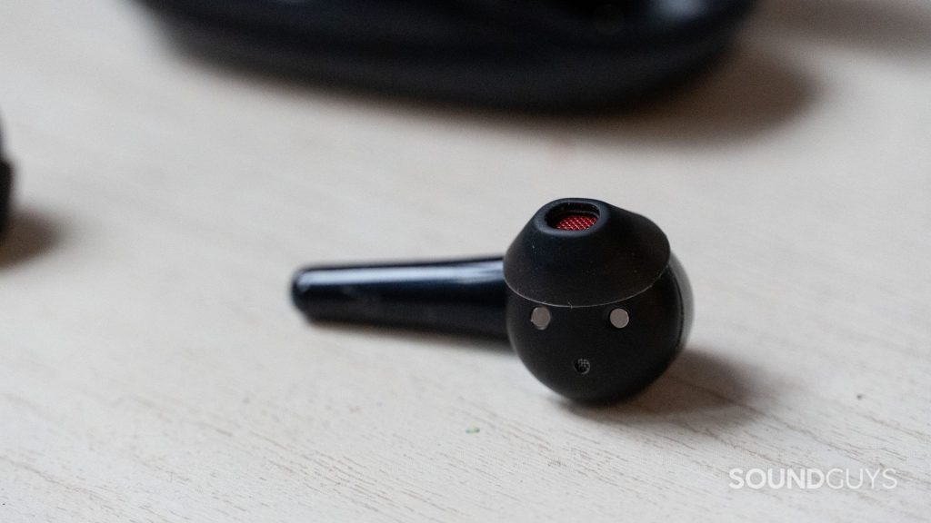 1MORE Comfobuds 2 earbud close up as it lays on a table.