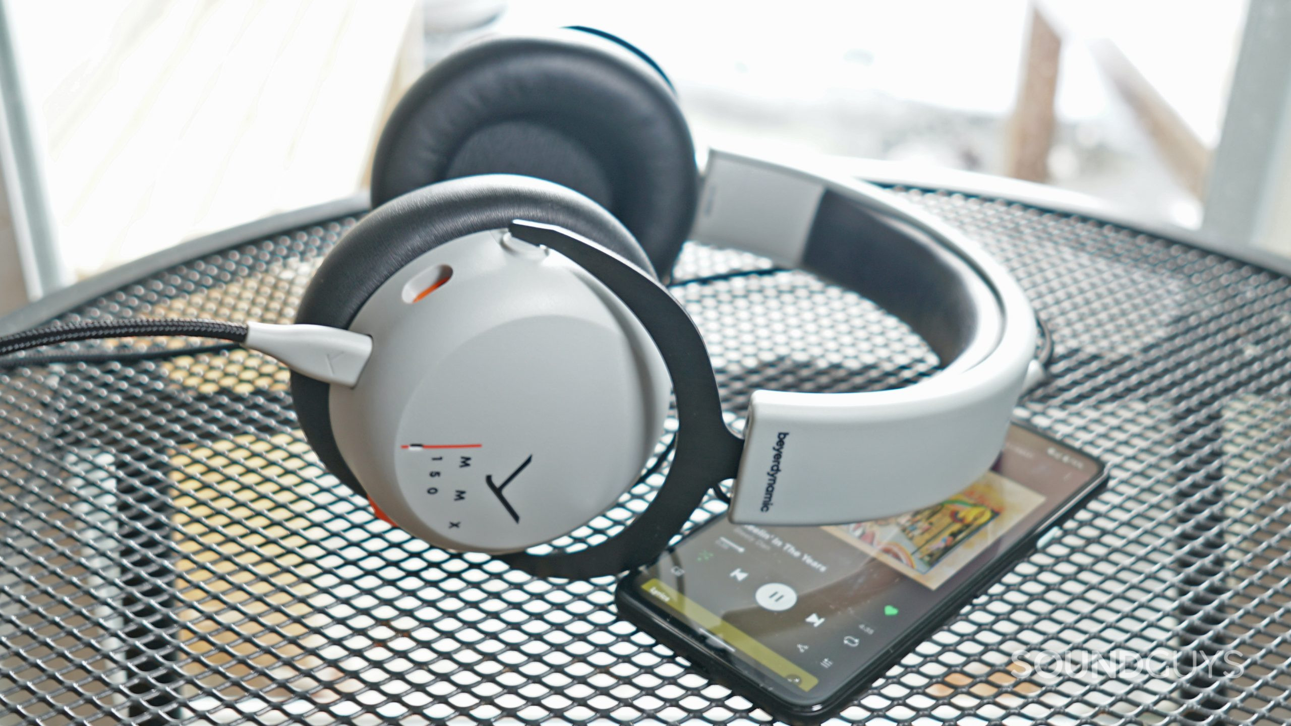 Beyerdynamic-MMX-150-phone-shot The Beyerdynamic MMX 150 lays on a metal table plugged into a Google Pixel 4a running Spotify.