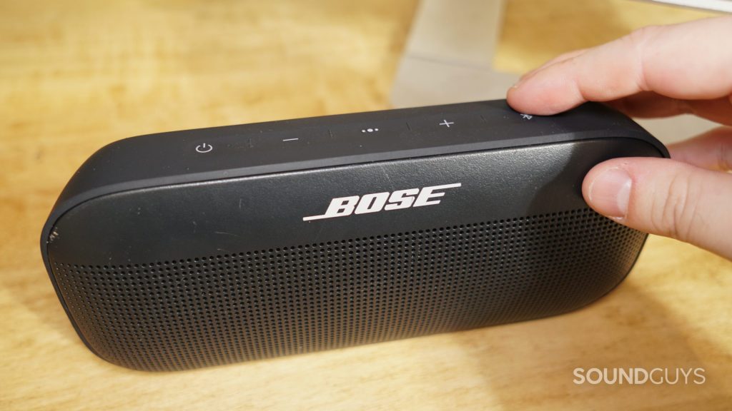 A photo of the top of the Bose SoundLink Flex Bluetooth speaker showing a finger pressing the Bluetooth pairing button.
