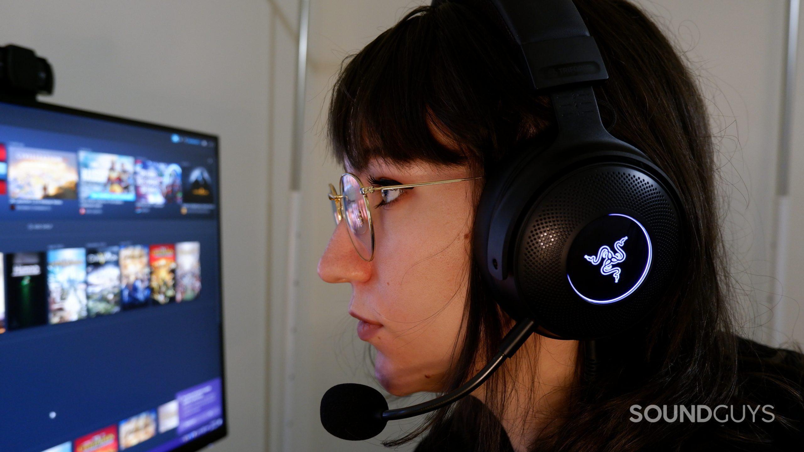 A person wearing a Razer Kraken V3 headset, looking at a computer stream with Steam open.