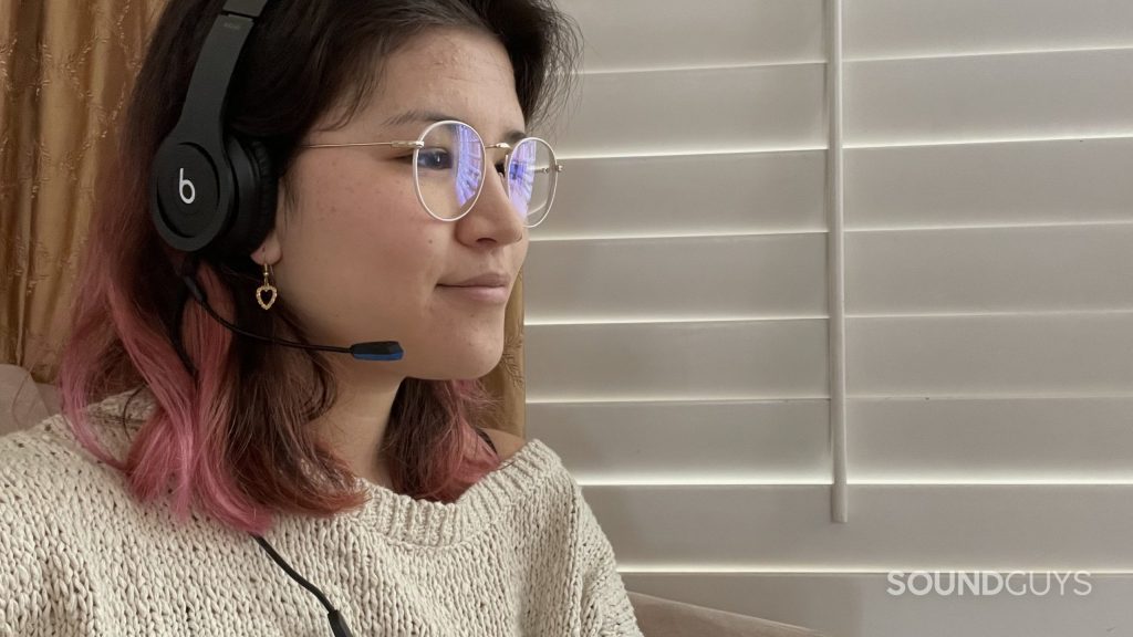 Woman wearing a pair of Beats headphones with the V-MODA BoomPro X plugged in.