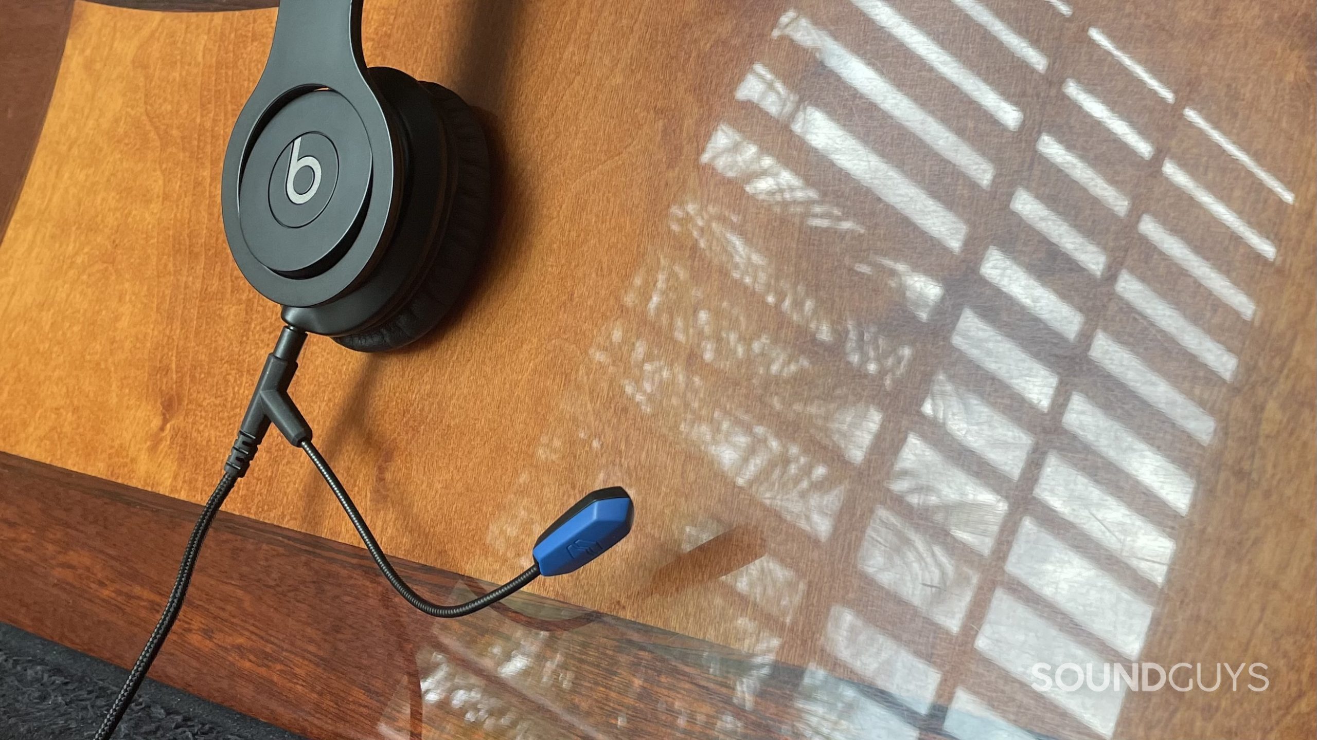 Beats hoofdtelefoons en V-Moda Boompro X-microfoon tegen een reflecterend houten oppervlak