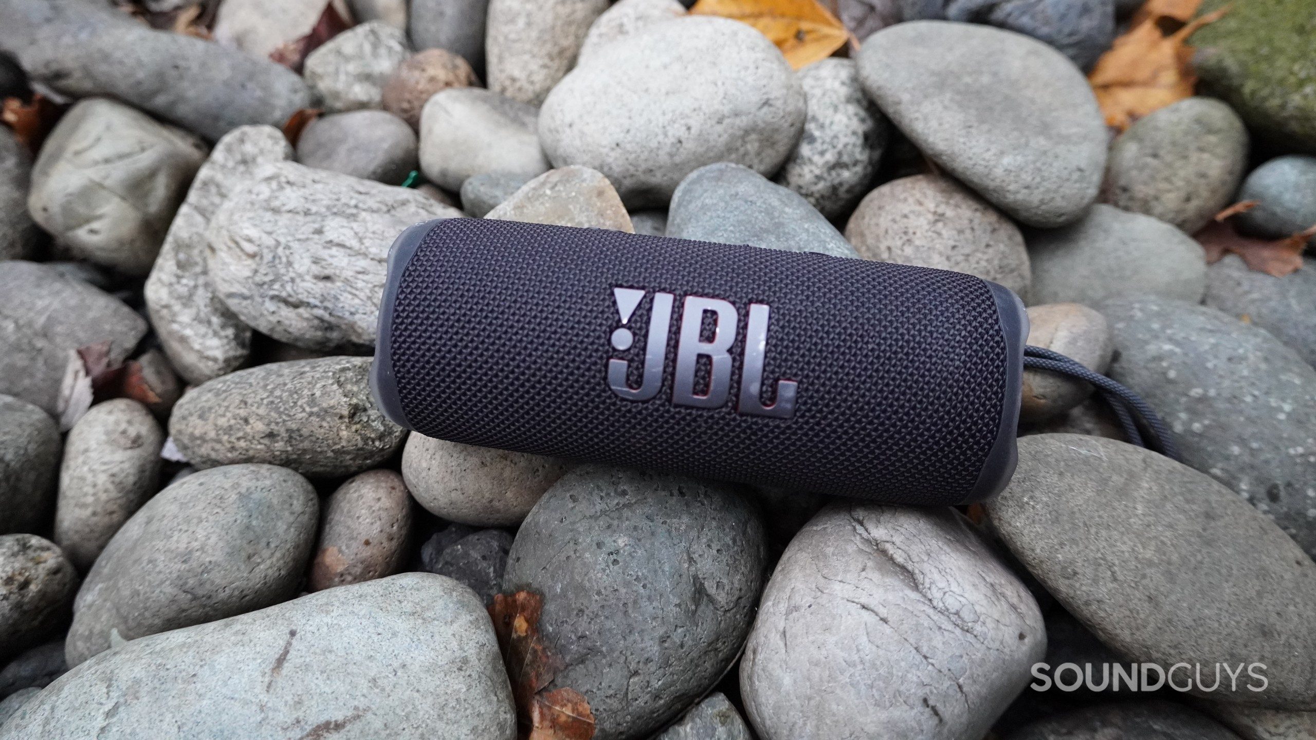 The JBL Flip 6 in black on a bed of flat stones.