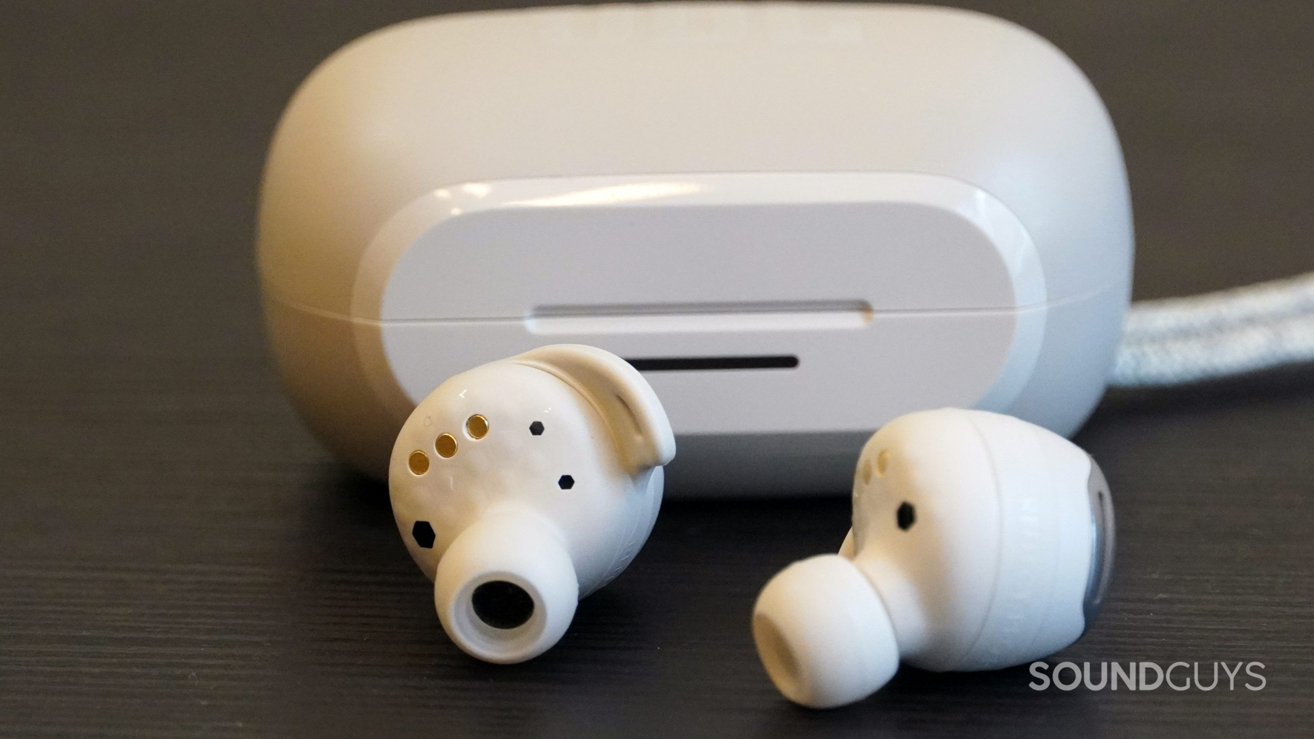 JBL Reflect Flow Pro earbuds on a black table with the case in the background.