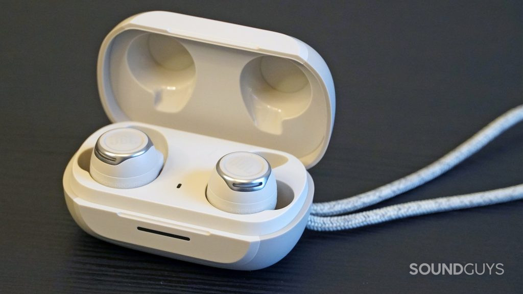 JBL Reflect Flow Pro earbuds sitting inside of their case on a table.