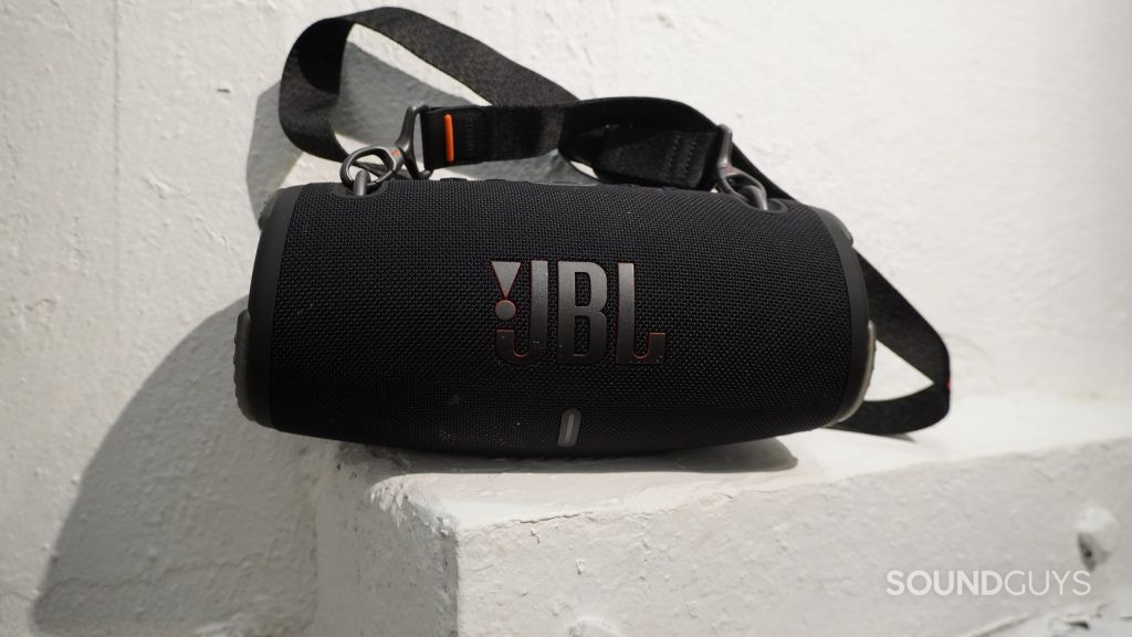 The JBL Xtreme 3 Bluetooth speaker sitting on a sloped white ledge next to a white wall.
