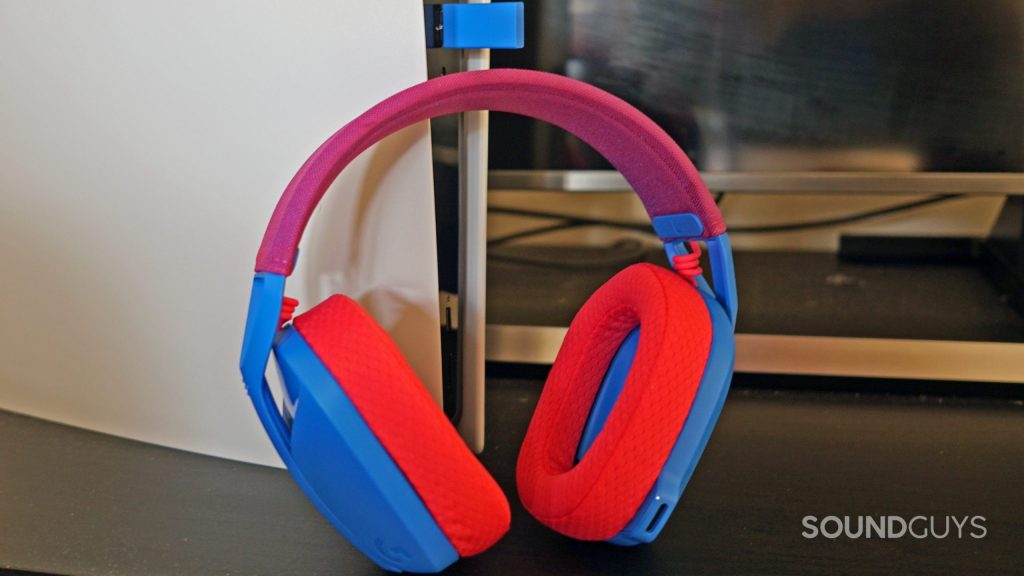 The Logitech G435 Lightspeed gaming headset leans on the front of a Sony PlayStation 5, with its dongle plugged in.