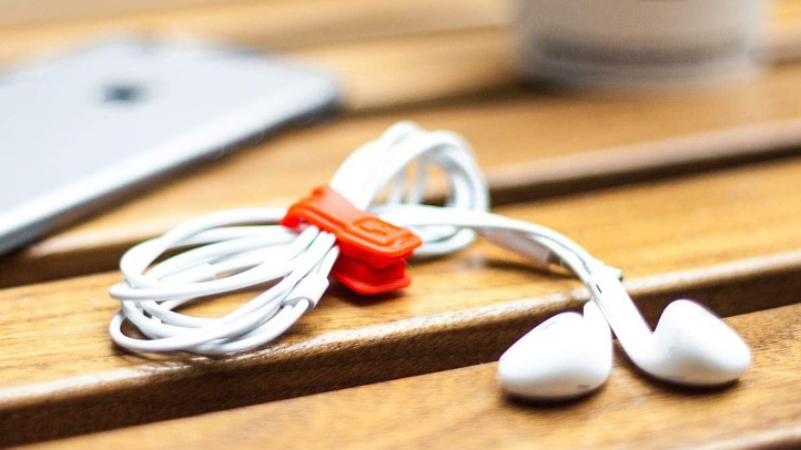 A set of wired earbuds are held together with the CLOOP Cord Keeper.