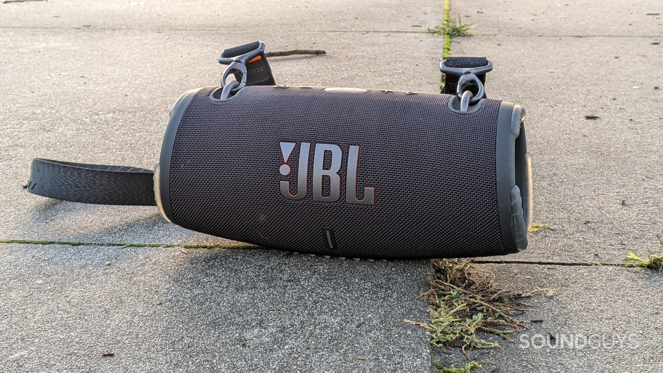 The JBL Xtreme 3 Bluetooth speaker sitting on concrete on a sunny day.