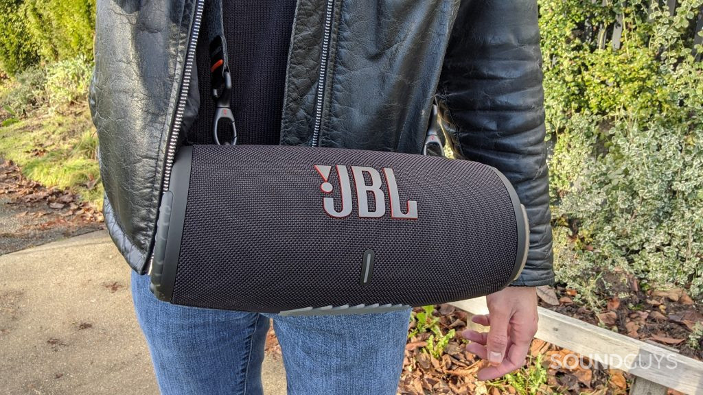 The JBL Xtreme 3 Bluetooth speaker being worn using its included carrying strap across the front of a person's torso.
