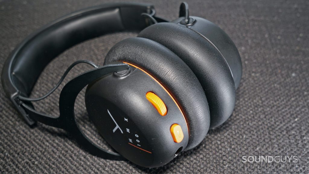 The Beyerdynamic MMX 100 gaming headset lays on a fabric surface with its volume dial and mute button in full view.