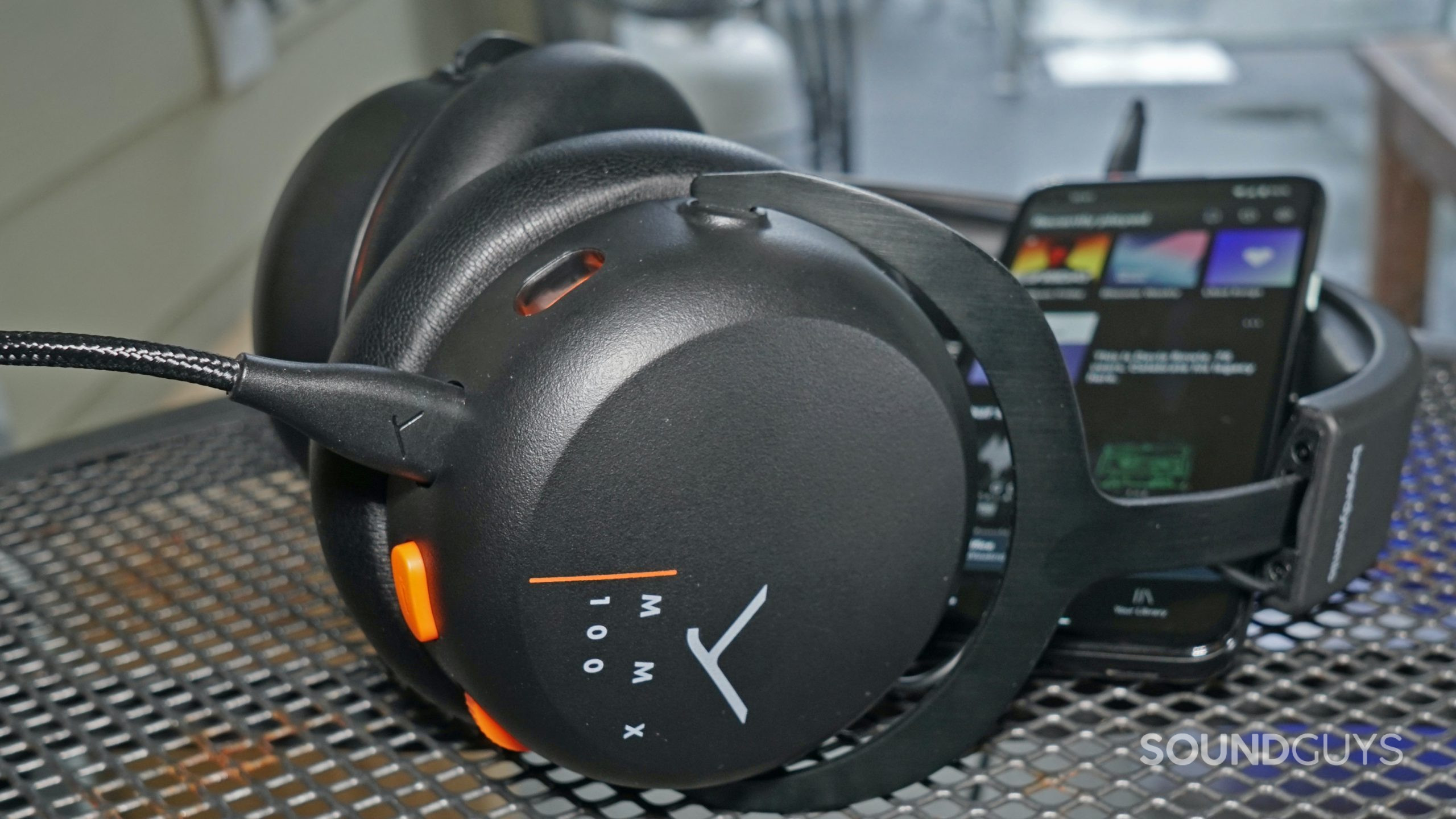 The Beyerdynamic MMX 100 gaming headset lays on a metal table next to a Google Pixel 4a.