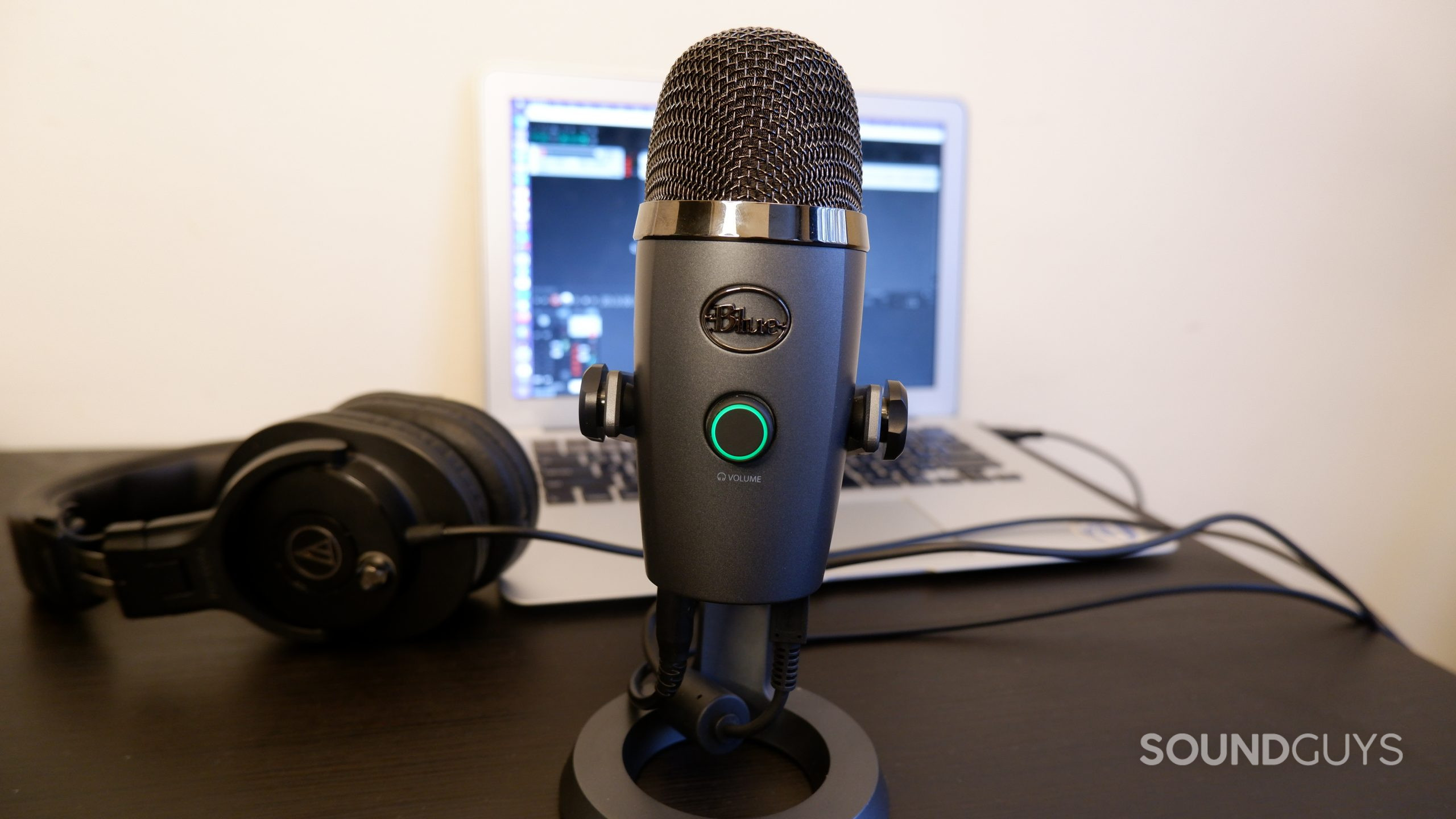 The Blue Yeti Nano sitting on a black table in front of a laptop and headphones
