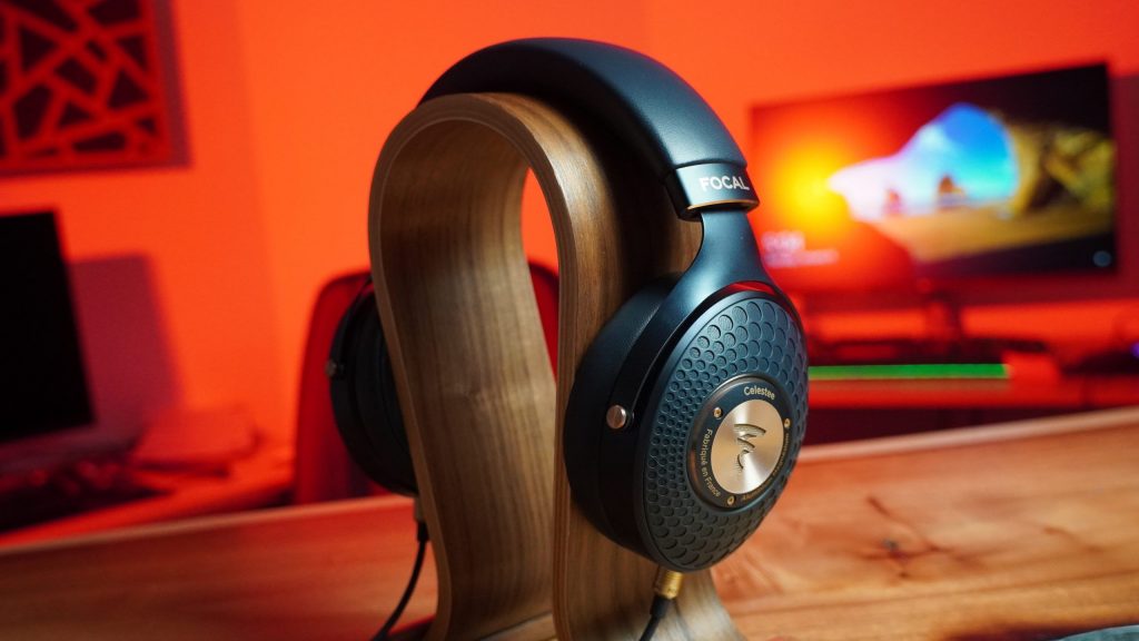 The Focal Celestee on a headphone stand in front of an illuminated red office background.