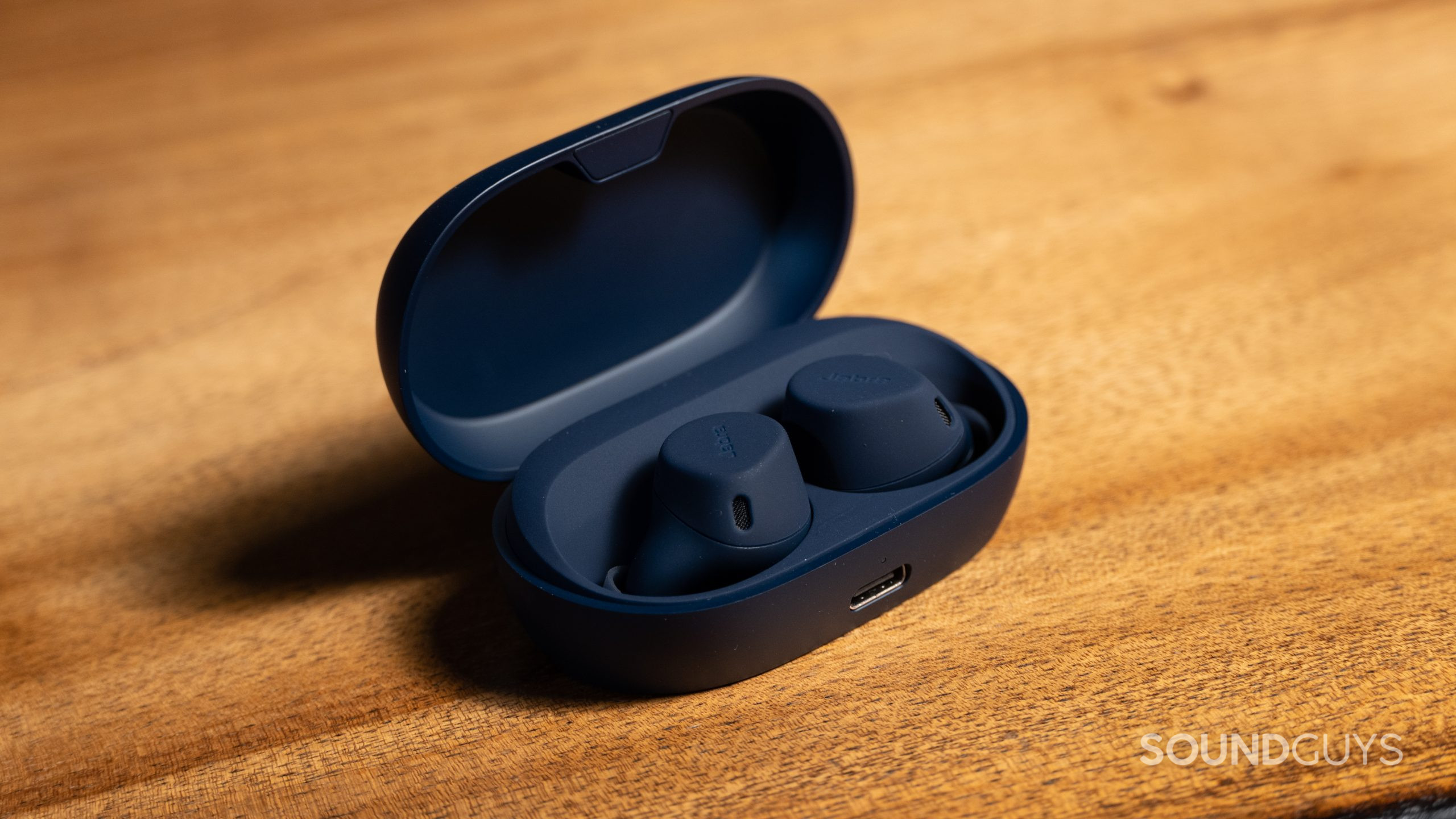 Jabra Elite 7 Active earbuds inside the charging case on a wood table