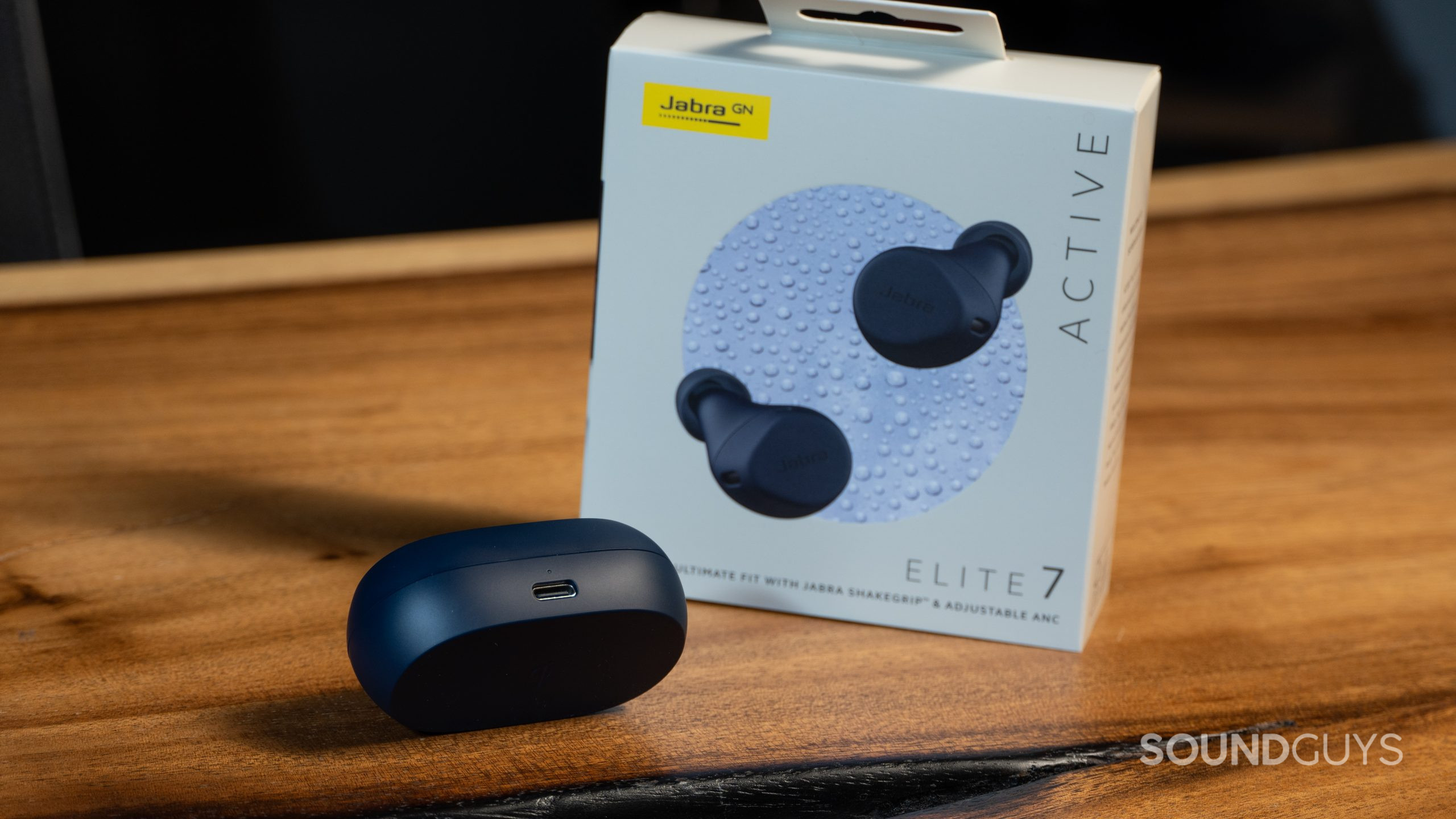 Jabra Elite 7 Active charging case on wood table next to product box.