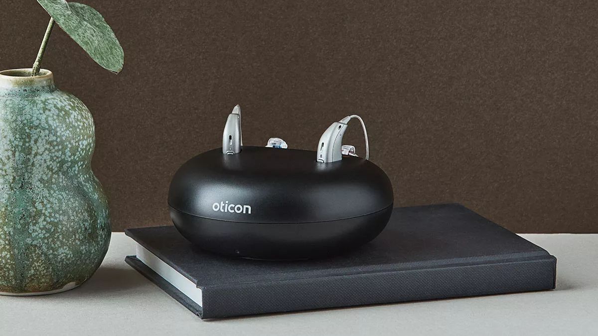 Oticon More hearing aids charging in their stationary charging station.