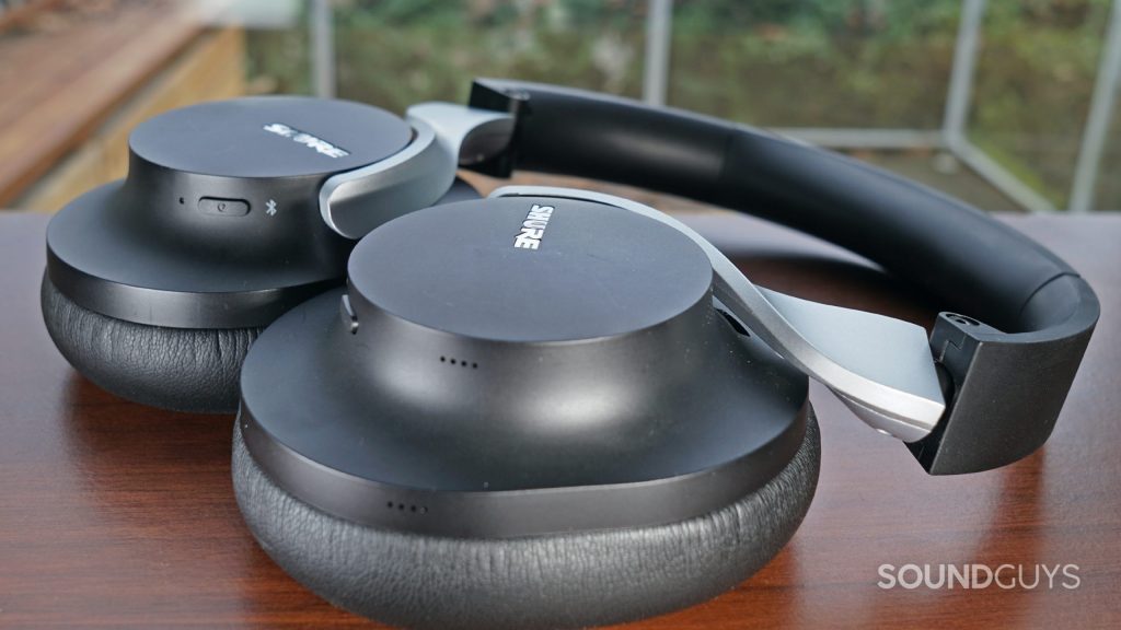 The Shure AONIC 40 lays flat on a wooden surface by a window.