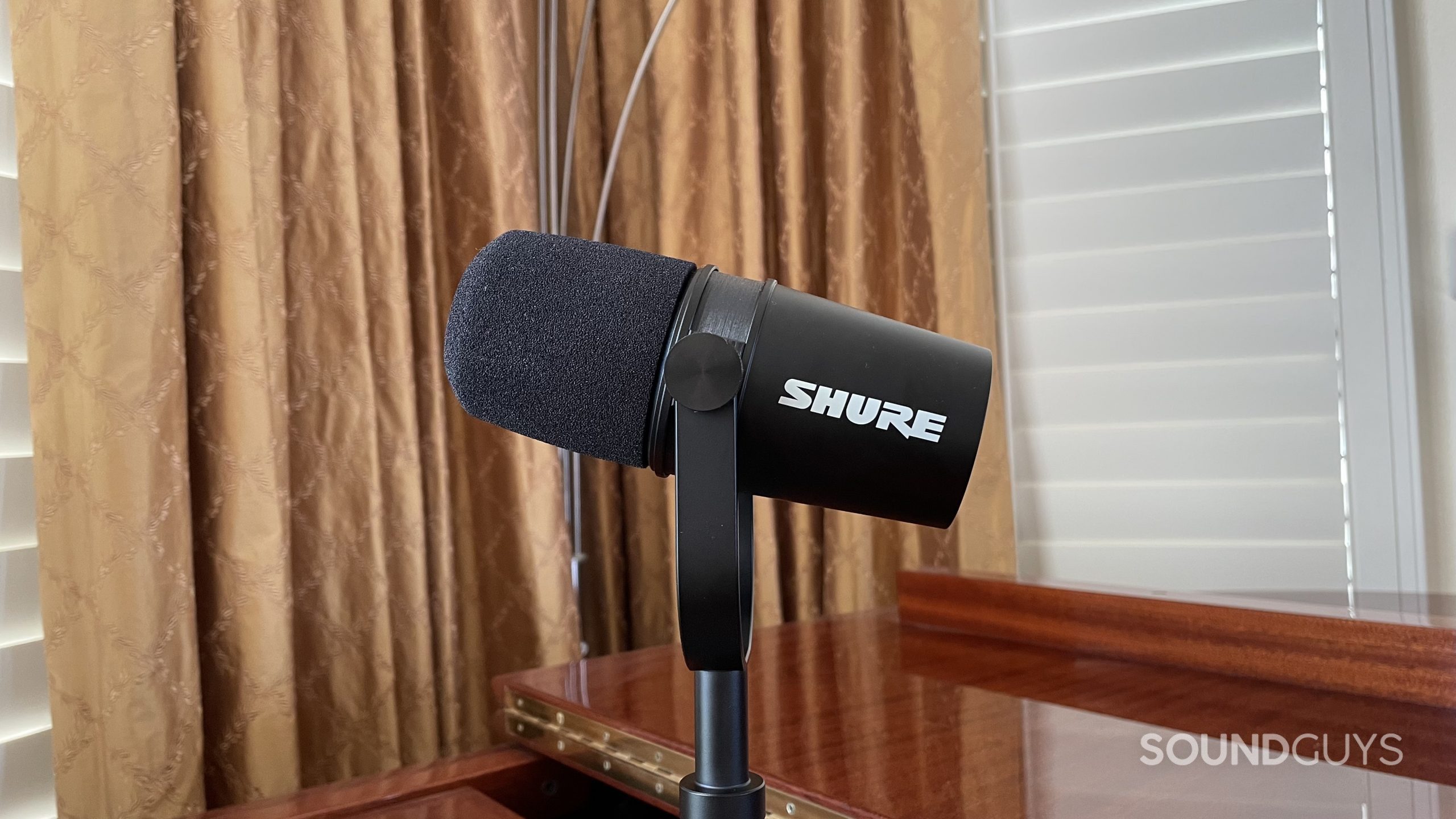 Shure MV7X with curtains and window blinds in the background.