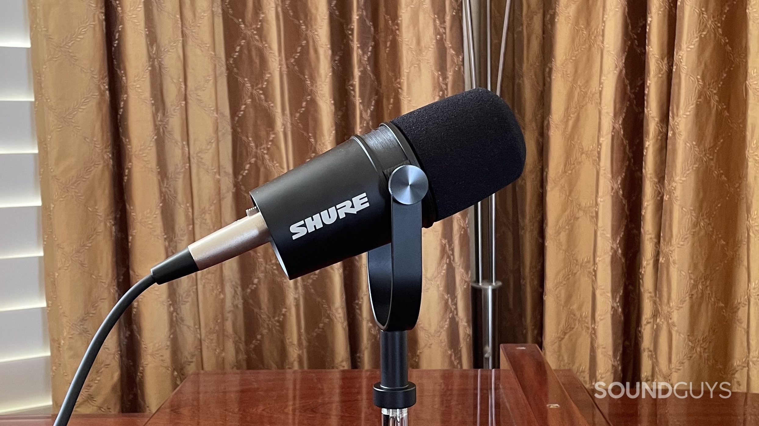 The Shure MV7X with curtains in the background.
