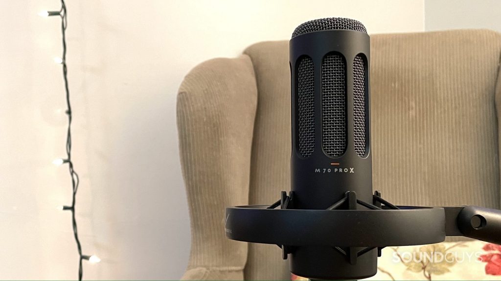 beyerdynamic M70 Pro X positioned upright in its mount with an armchair, pillow, and string of lights in the background.