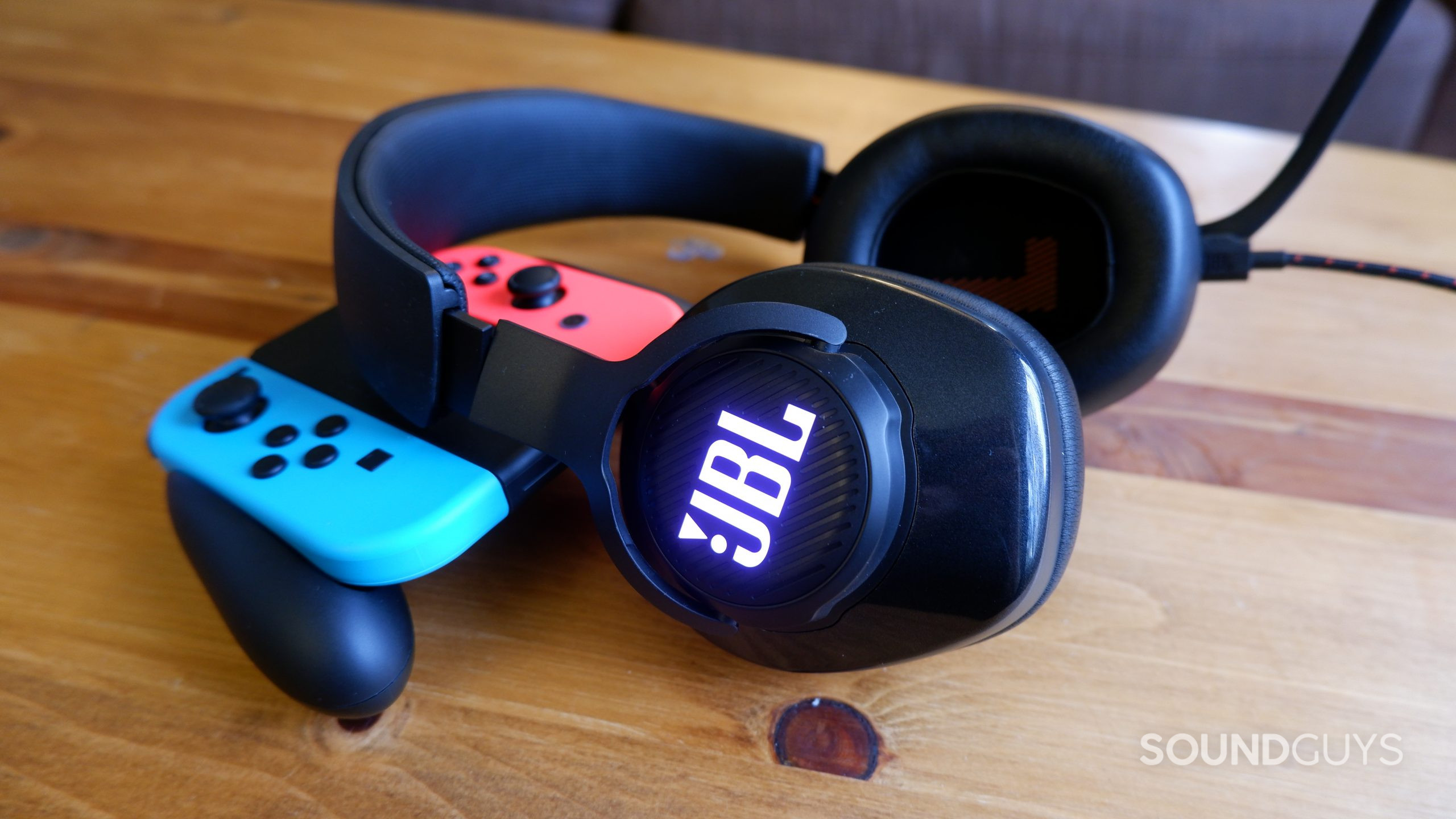 The JBL Quantum 400 headset laying on a wooden coffee table against a Nintendo Switch controller.