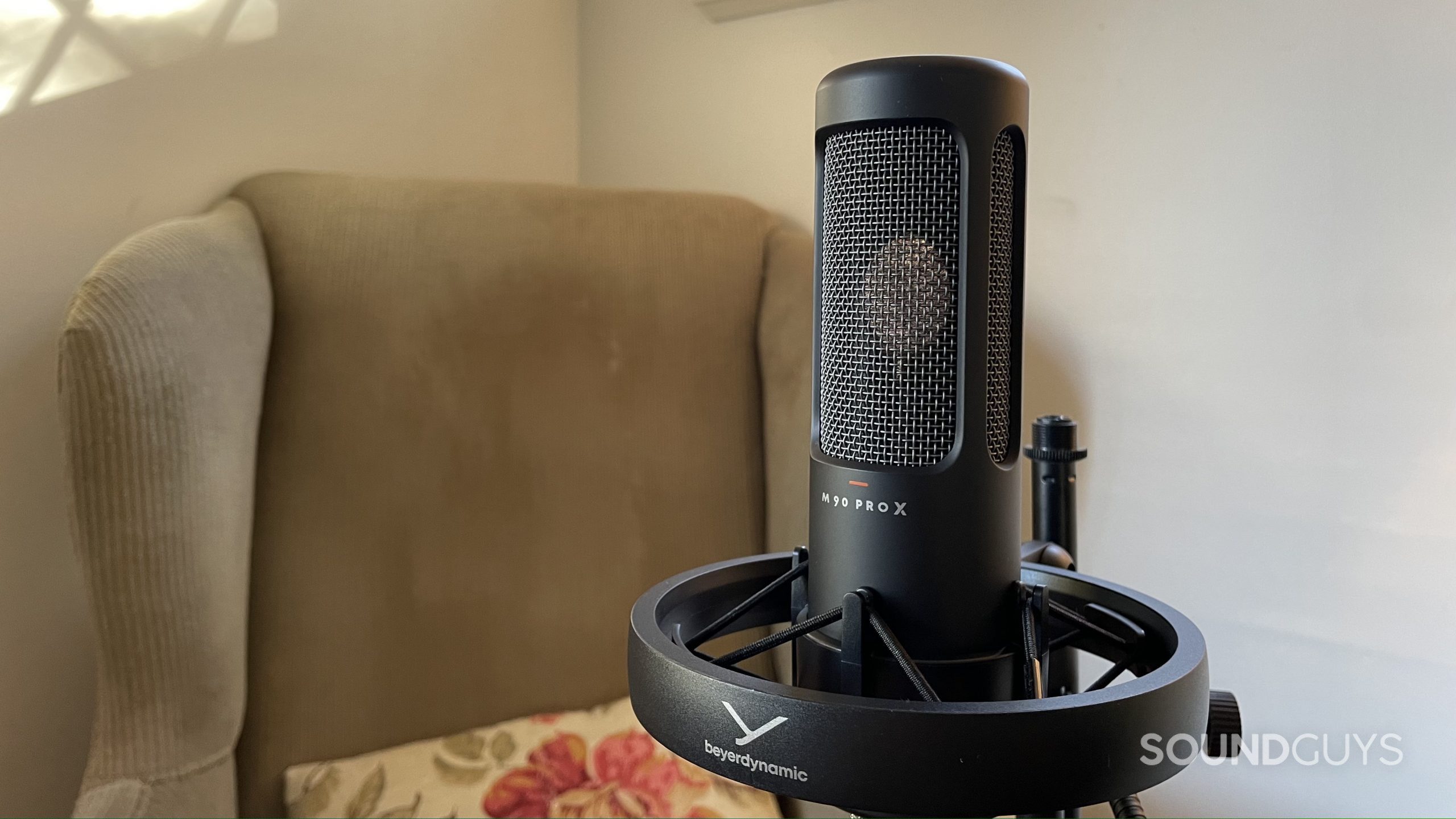 Beyerdynamic M90 PRO X in its shock mount with an armchair in the background.
