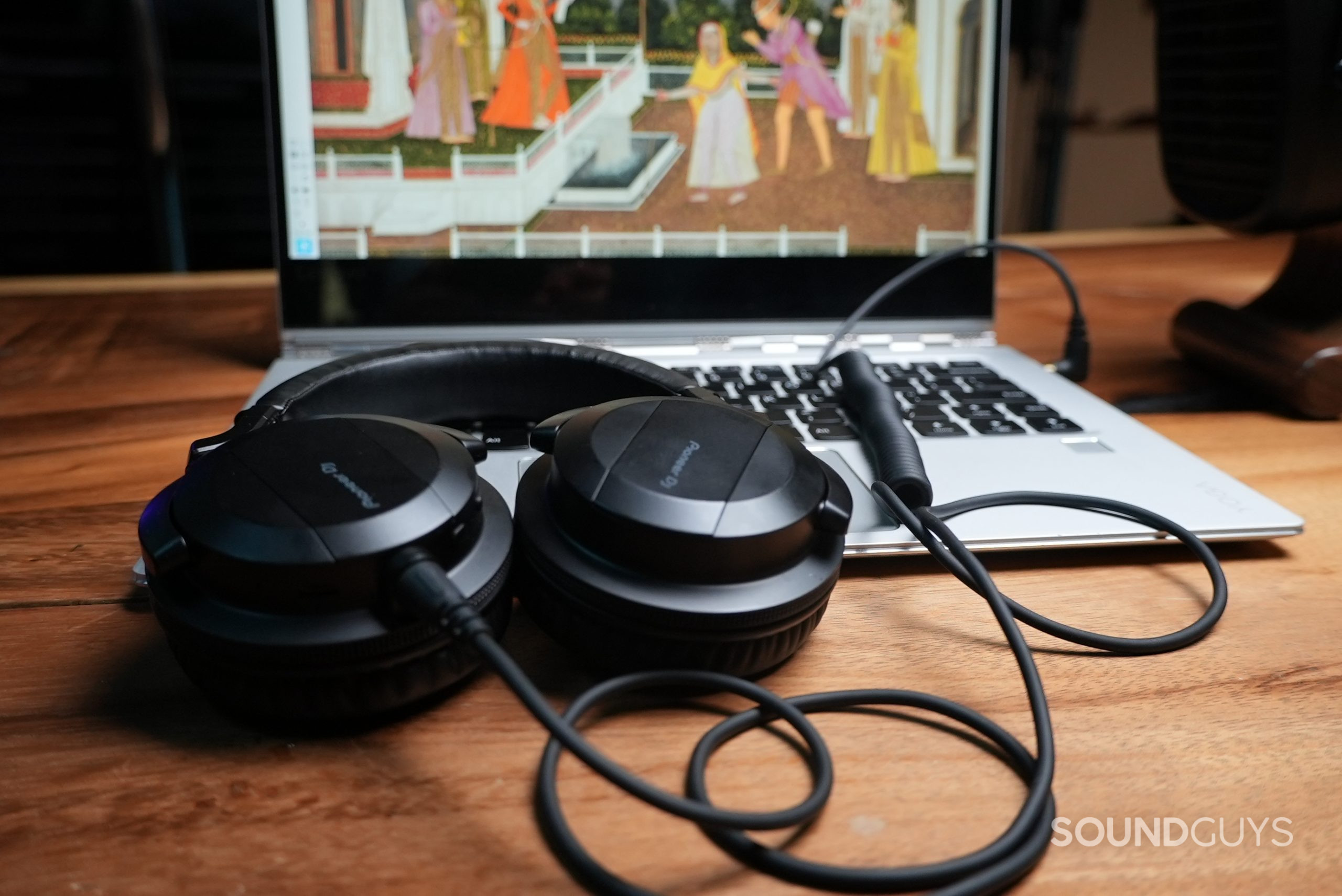 The Pioneer HDJ-CUE1BT lying on a laptop connected via a coiled wire to the laptop's headphone port.