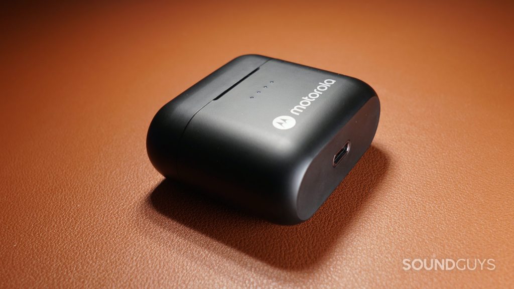 The case of the Motorola Moto Buds S ANC lays on its side on a leather surface, showing its USB-C charging port.