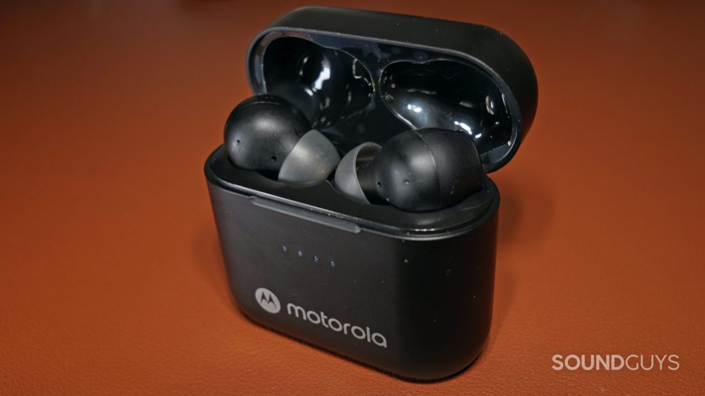 The Motorola Moto Buds S ANC sit in the case on a brown leather surface.