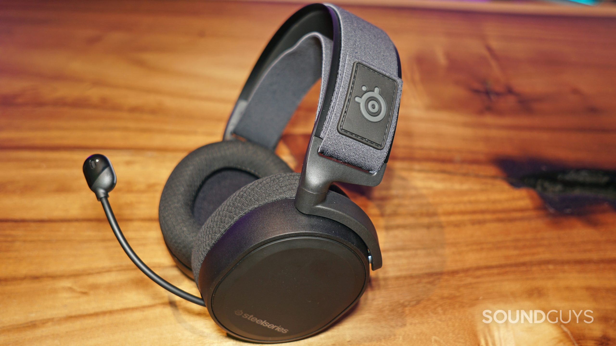 The SteelSeries Arctis 7+ lays on a wooden table.