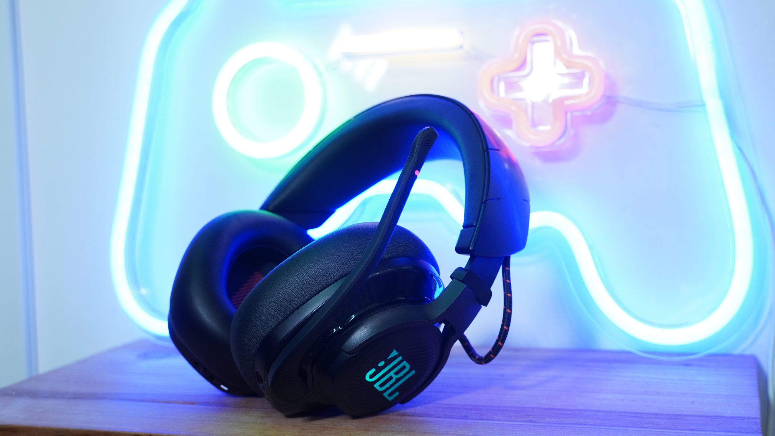 The JBL Quantum 600 in front of a neon game controller sign