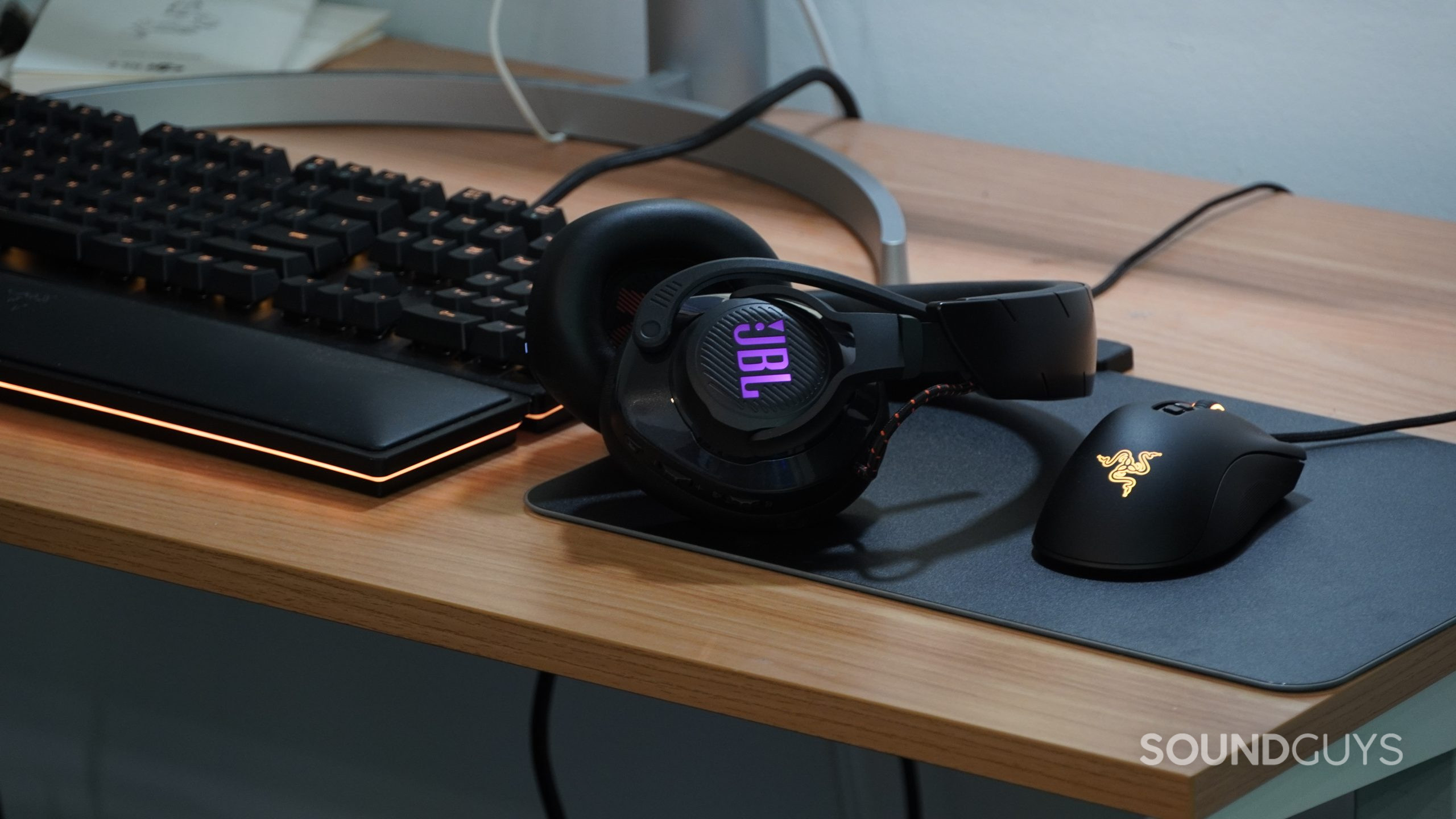 Photo of the JBL Quantum 600 on a desk next to some Razer peripherals