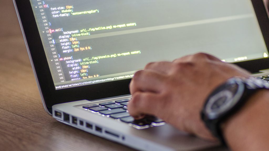 A man types CSS into a nondescript editor for web development.