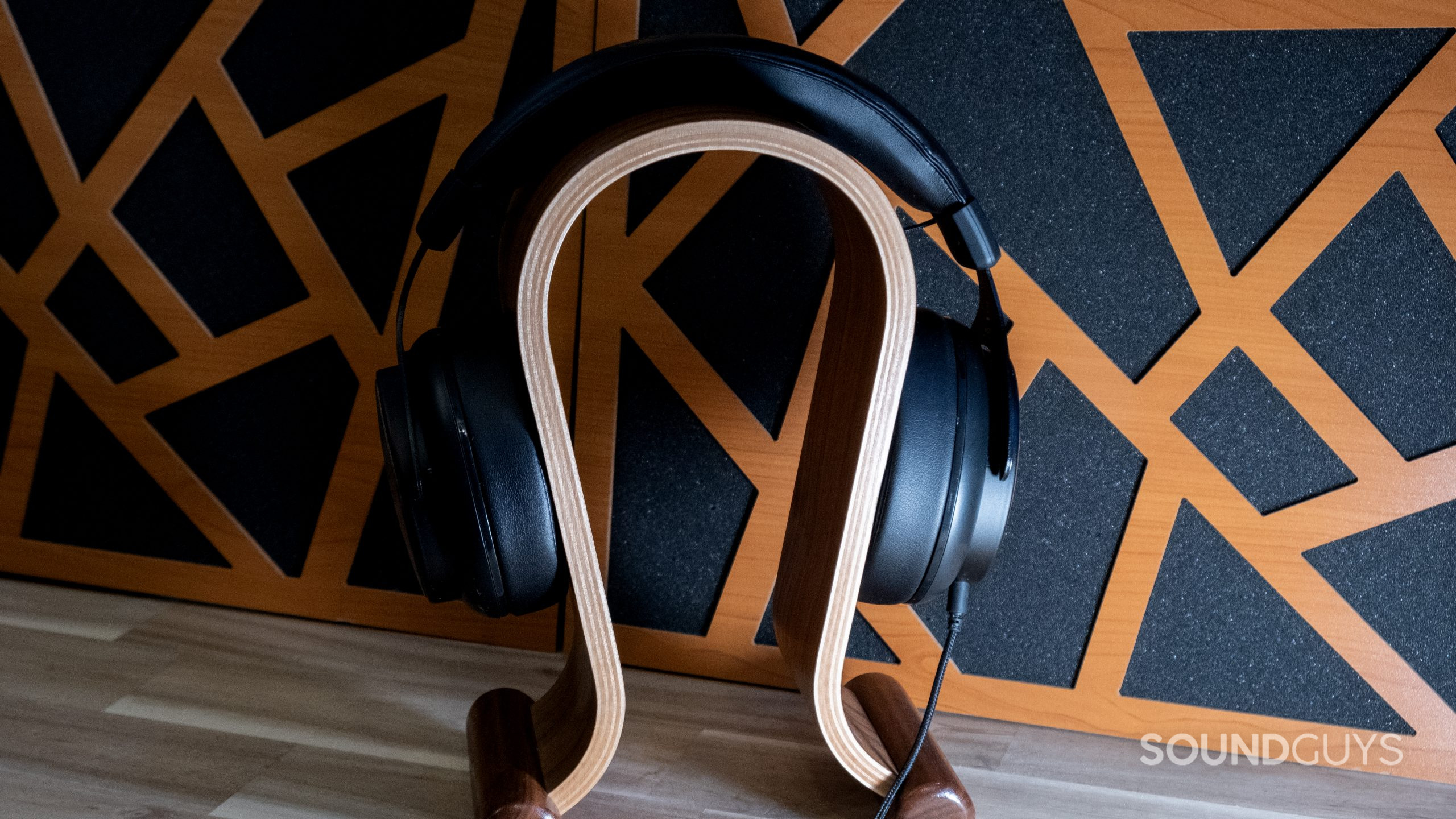 Shot head on the Thinksound ov21 is fitted over a wooden headphone stand with acoustic panels behind.