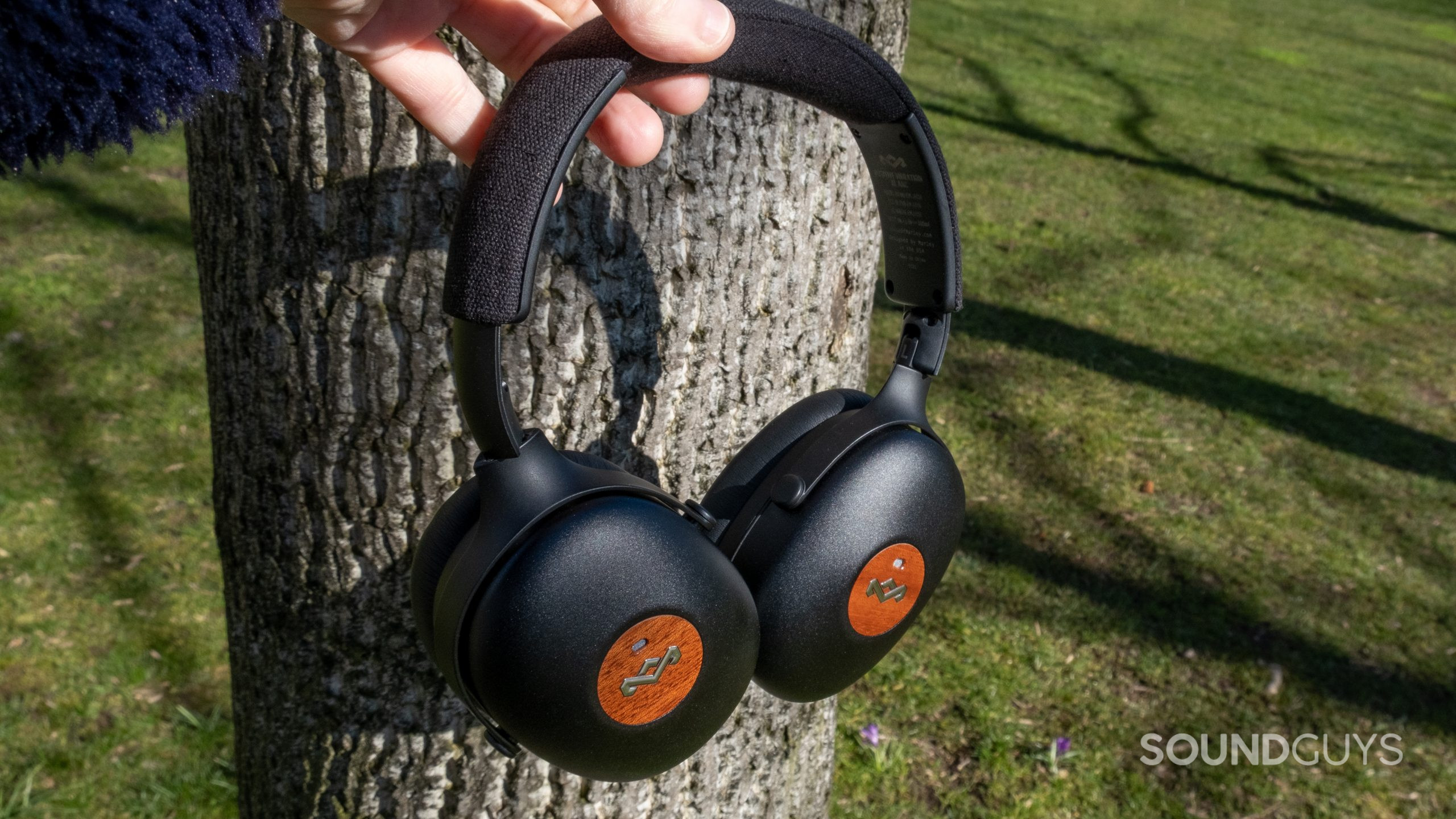 The House of Marley Positive Vibration XL ANC held up in front of a tree and grass with the ear cups rotated flat.