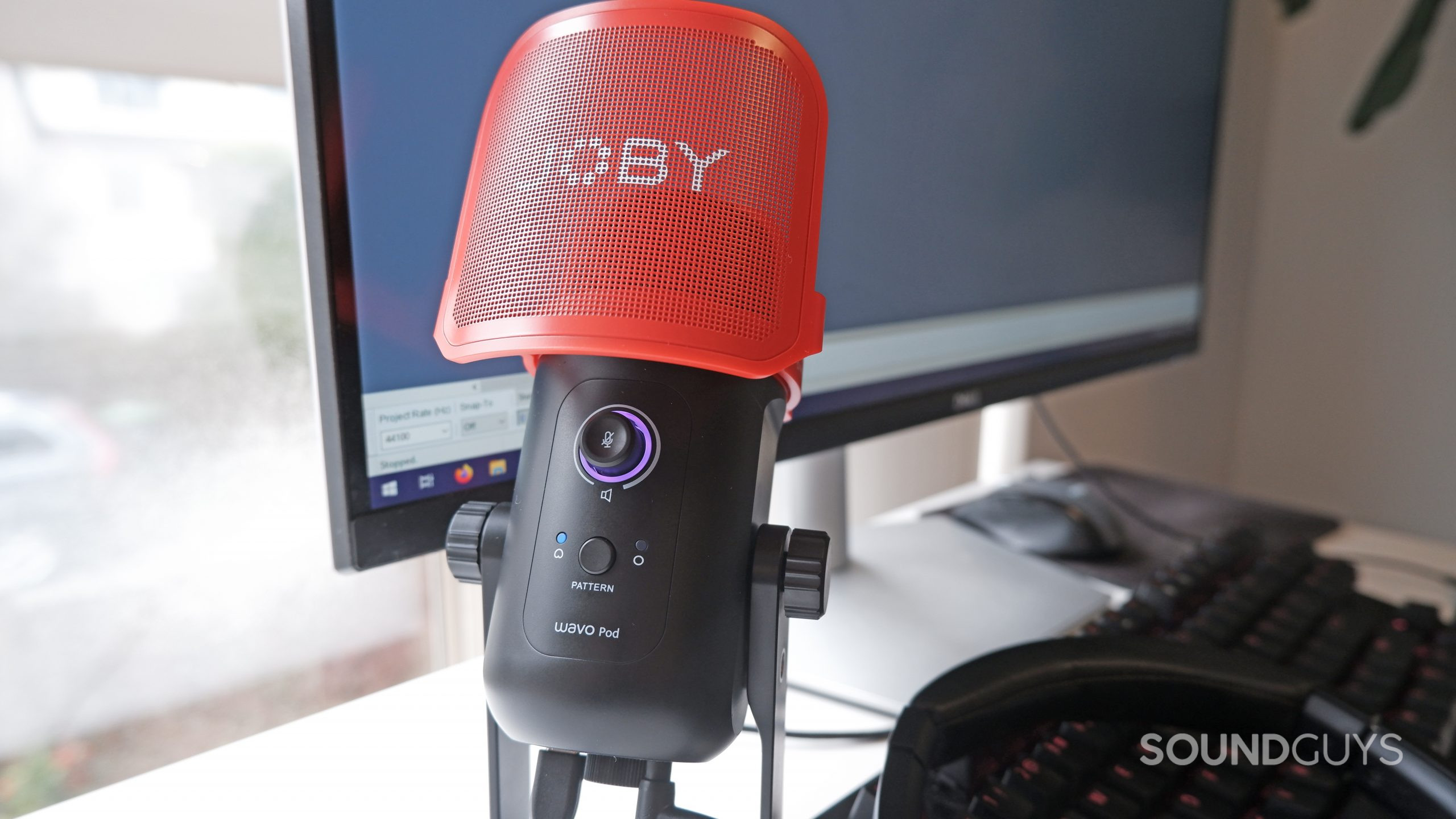 The JOBY Wavo POD with the gain function turned on, sitting on a desk in front of a computer.