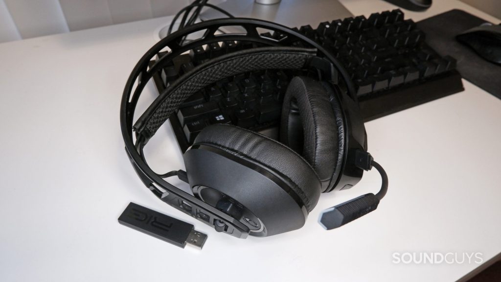 The RIG 700 PRO HS resting on a keyboard on a desk, with the RF dongle next to it.