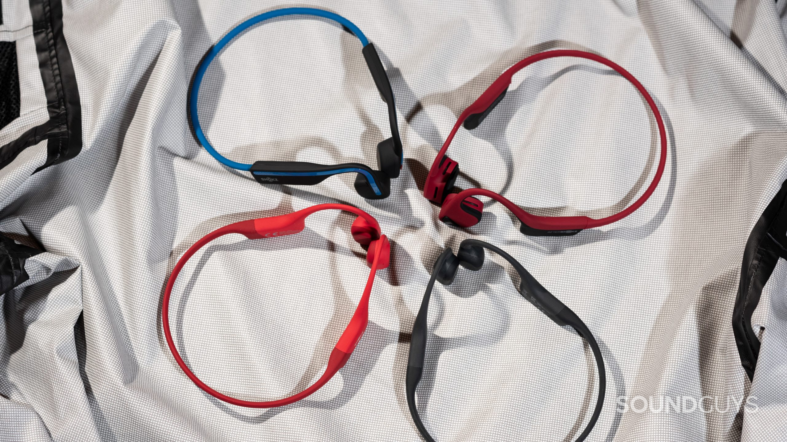 A selection of Shokz/AfterShokz bone conduction headphones in a circle, including the OpenRun, OpenMove, Air, and Aeropex.