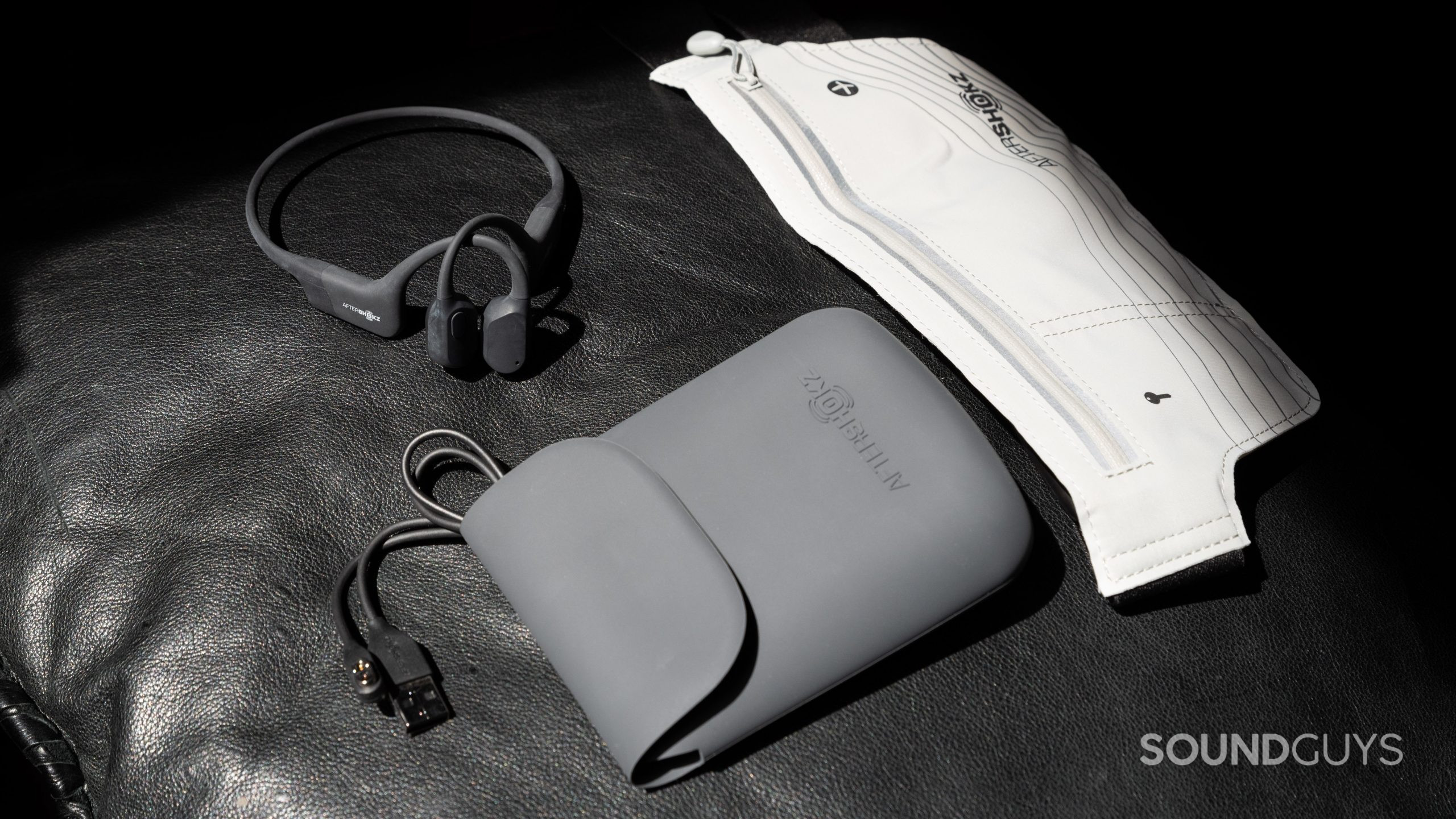 The Aftershokz Aeropex bone conduction headphones accessories lay on a black surface.