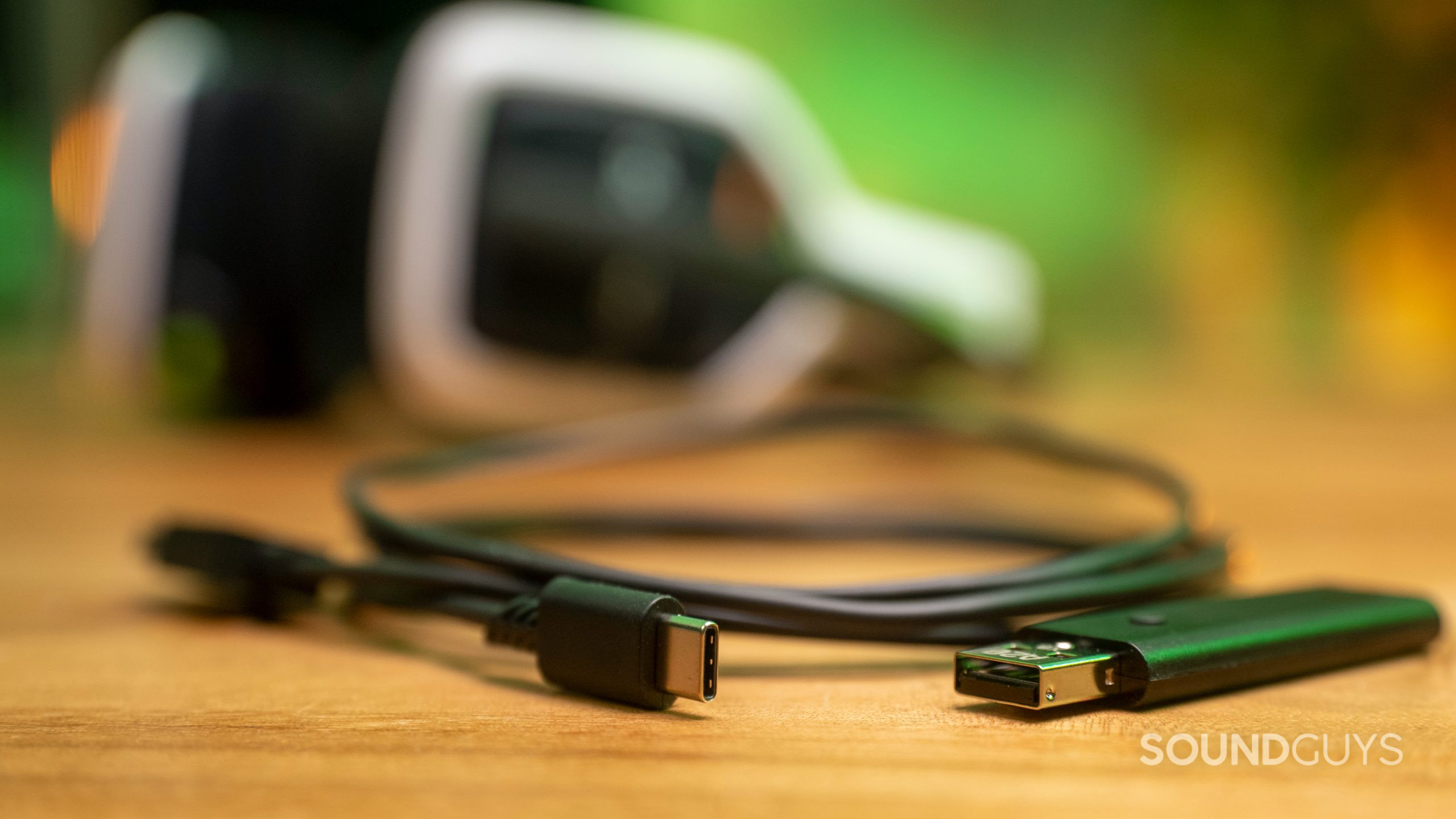 The wireless dongle for the Astro A20 lays in the foreground, with the headset behind it.