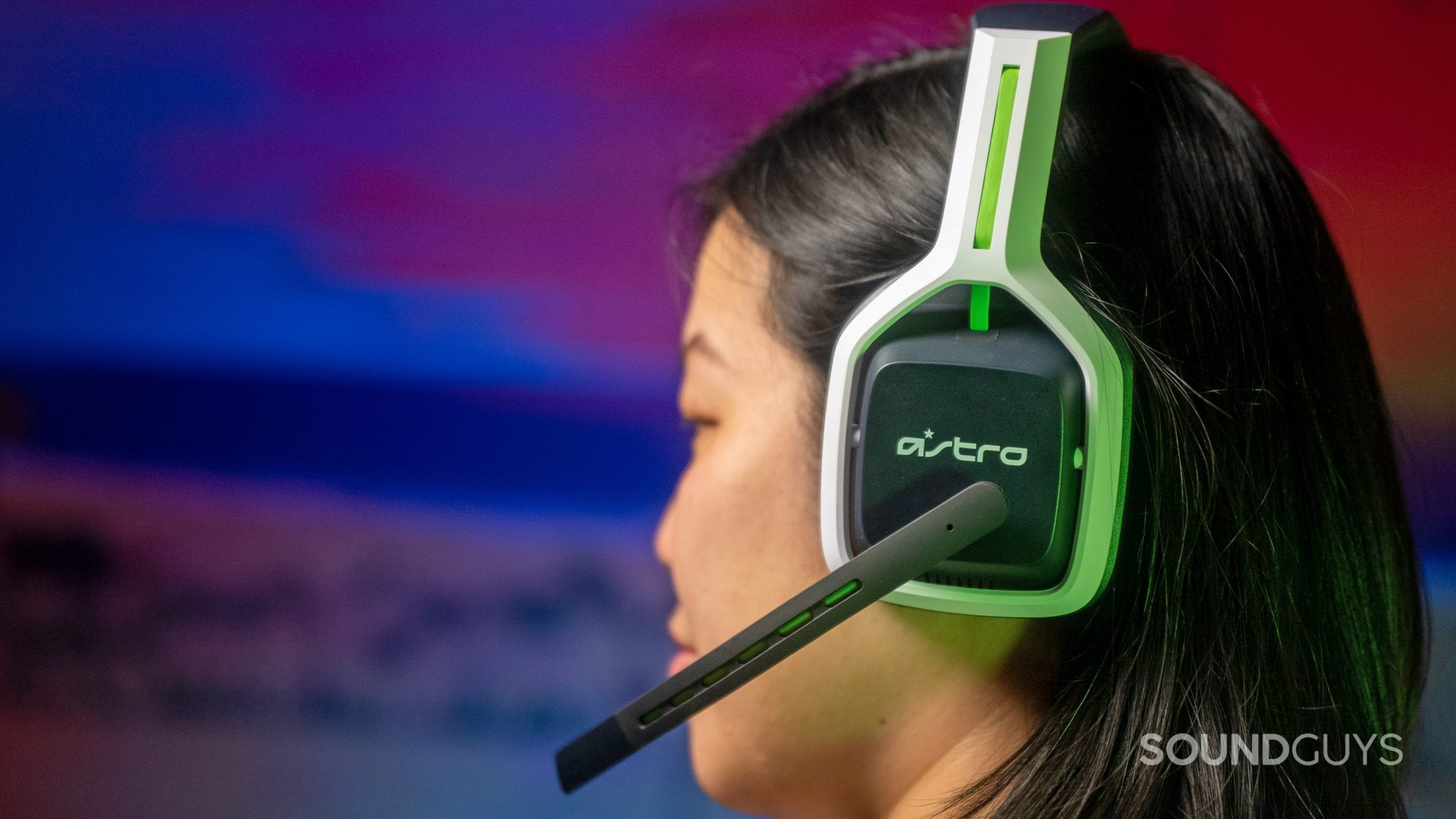 A woman wears the Astro A20 gaming headset with the microphone flipped down.
