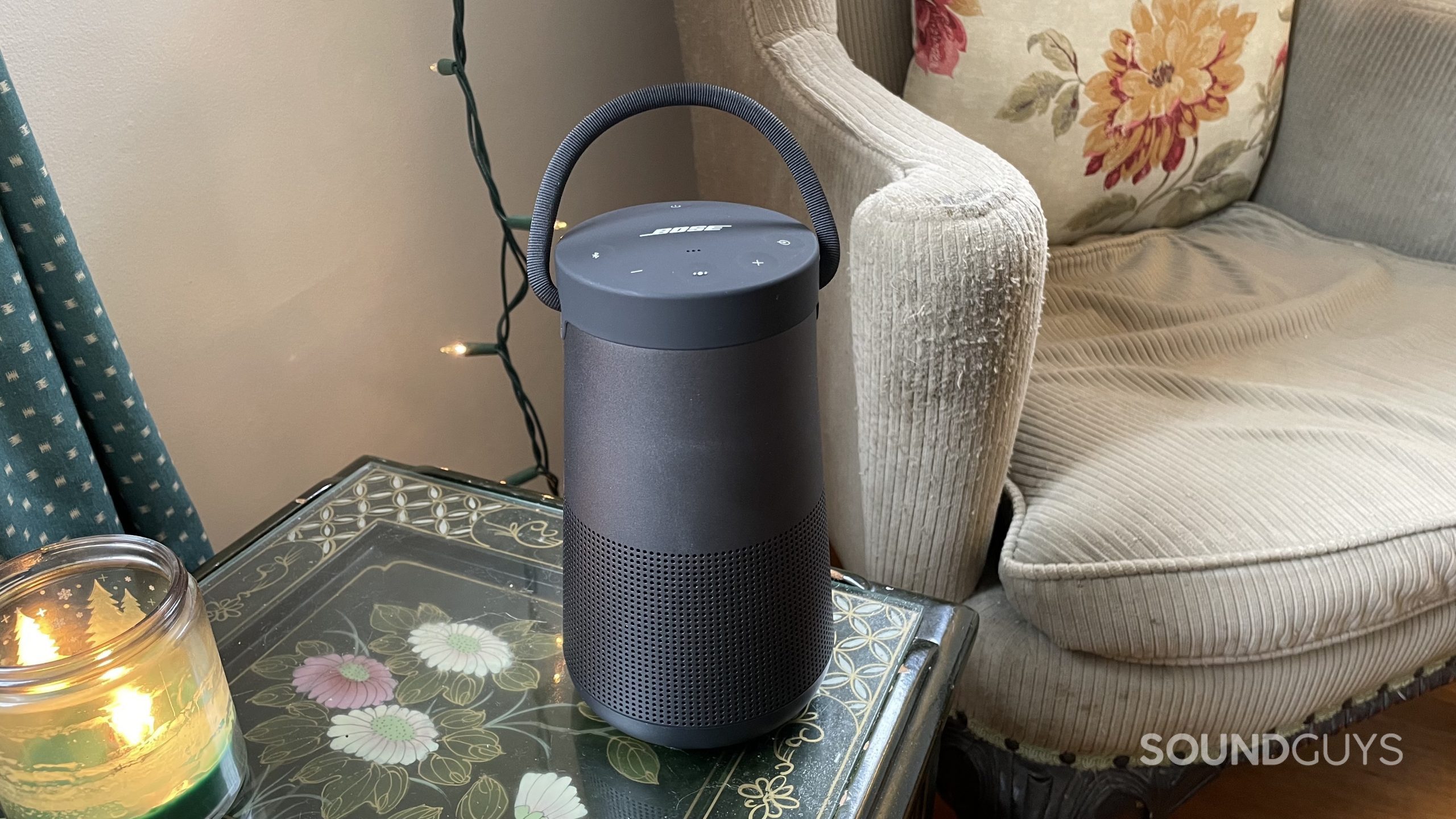 Bose SoundLink Revolve+ II sitting on a side table with a candle.