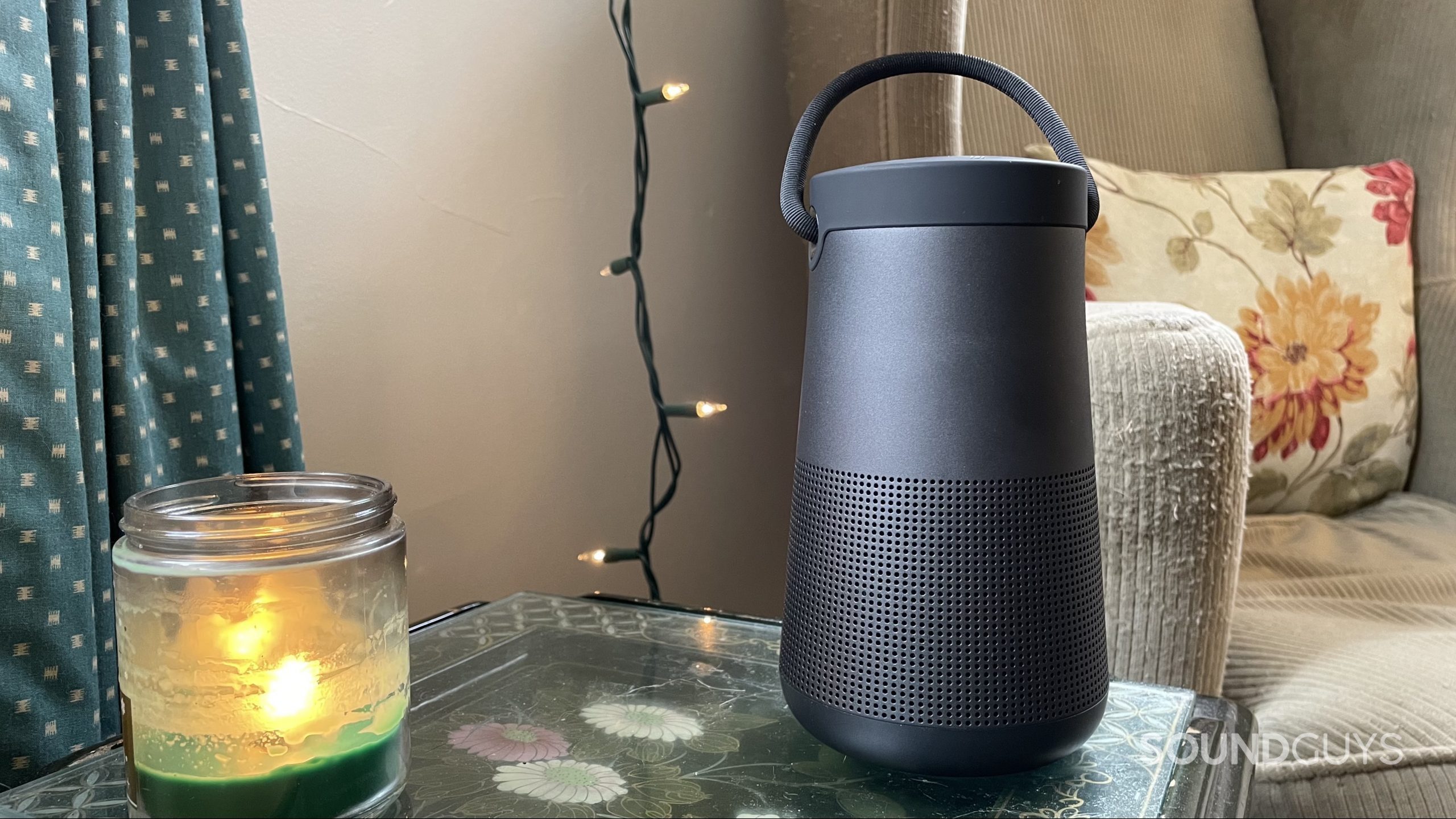 Bose SoundLink Revolve+ II on a side table with a candle.