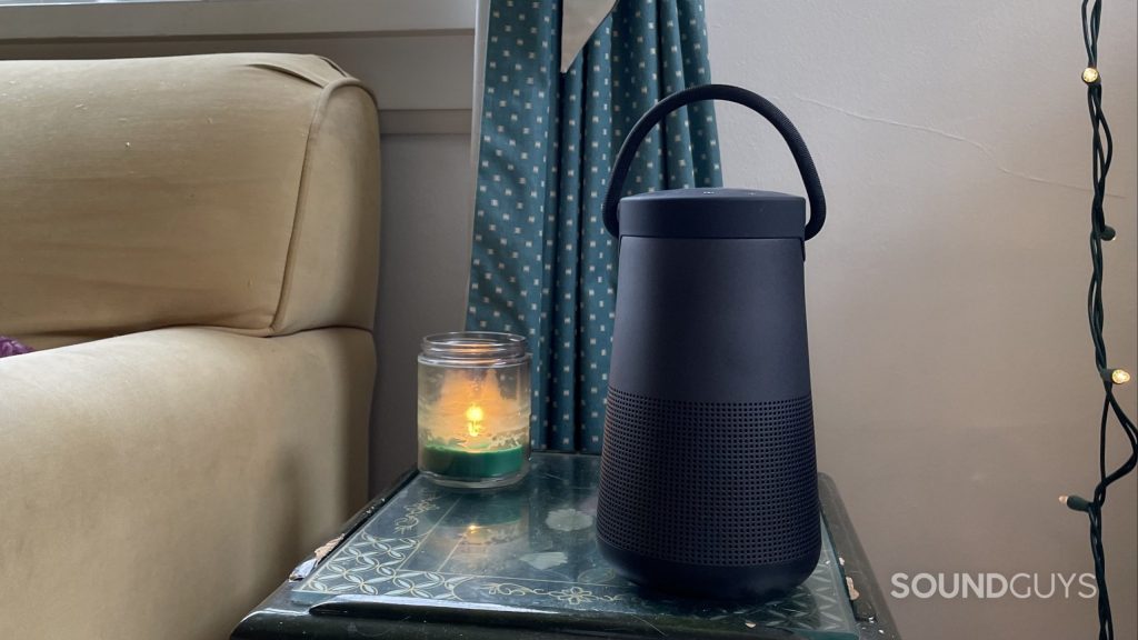 Bose SoundLink Revolve+ II sitting on a side table with a candle.