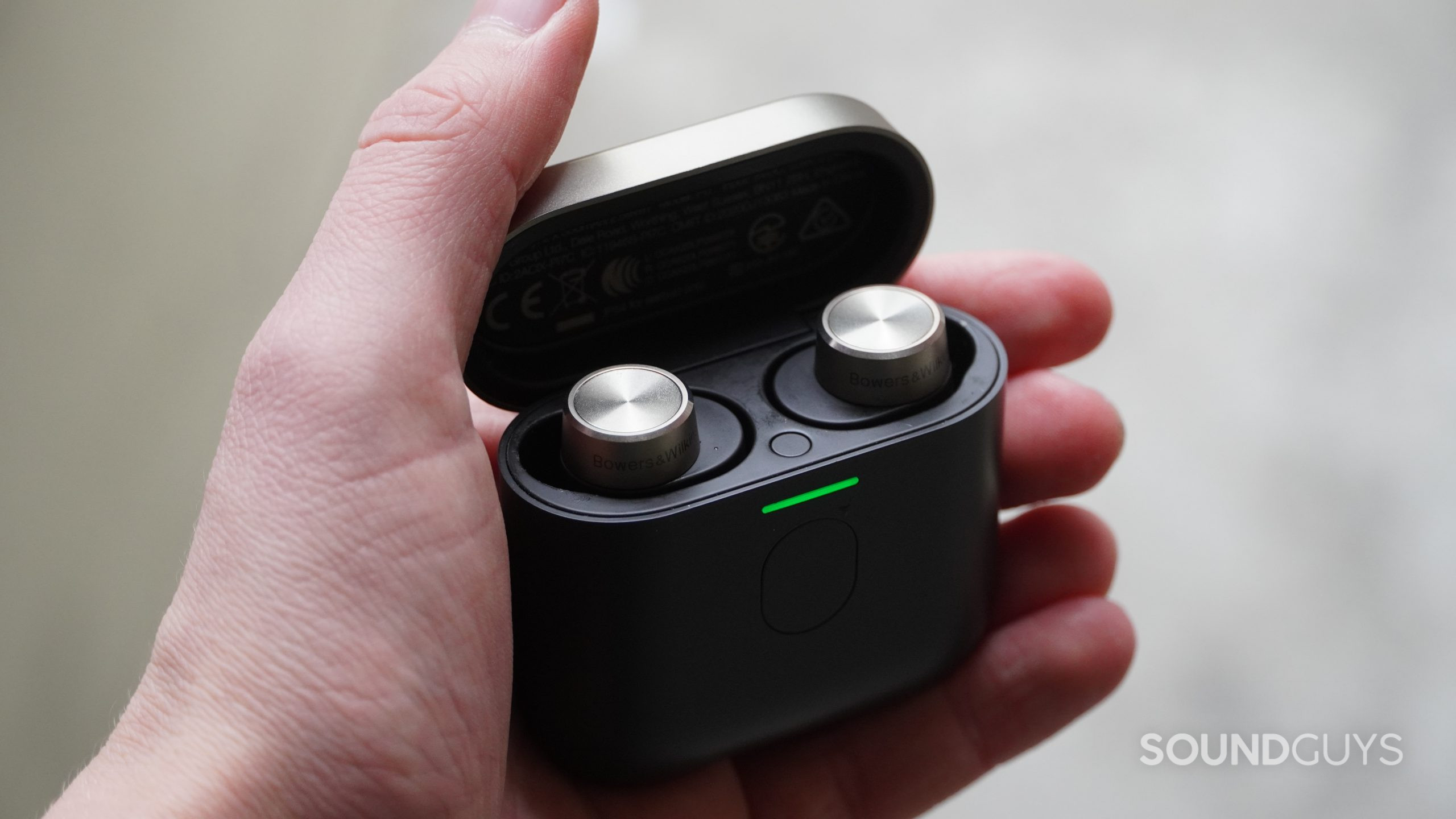 Bowers and Wilkins PI7 in charging case being held in a hand.